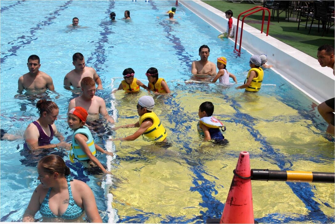 Marine Wing Support Squadron 171 Marines and volunteers swim with Yahata Gakuen children's home children during a community-relations event at the WaterWorks Pool here July 21, 2012. The children came aboard station for a day of fun with the Marines during a pool party and traditional American barbecue.