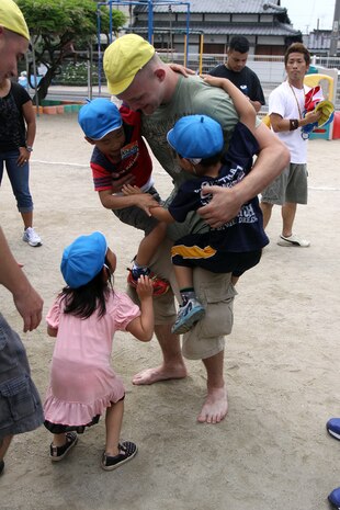 Children cling to Jacob McClinton, a volunteer, during a community relations event at the Higashi Hoikuen Preschool in Iwakuni June 15, 2012. The volunteers spent the morning teaching the children letters and words in English. Once they finished, they participated in a relay race, played with the children on monkey bars and ropes. The event helped the children and the volunteers learn about each other’s cultures.