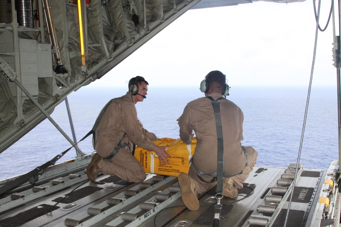 Lance Cpls. Eric Bruning and Vinson Gallardo with Marine Aerial Refueler Transportation Squadron 152 carry a life raft also containg food and water as well as a radio and other various survival aids to be dropped to the two men adrft below during a search and rescue mission June 6, 2012. The raft was dropped close enough for the two men adrift to get to easily and finialy recieve fresh water and food.