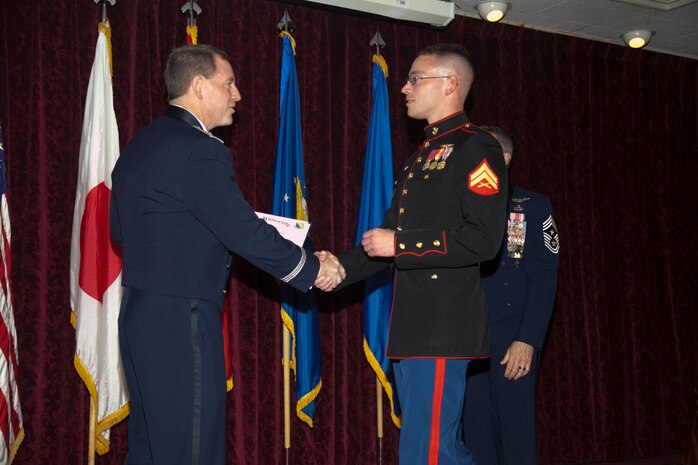 Cpl. Christopher R. Oliver receives his diploma from Brig. Gen. James B. Hecker during the Airman Leadership School graduation Oct. 25 at the Rocker NCO club on Kadena Air Base. Oliver was one of two Marines to attend the ALS for the first time in six years. Oliver is a crew master for the KC-130J Hercules transport aircraft with Marine Aerial Refueler Transport Squadron 152, Marine Aircraft Group 36, 1st Marine Aircraft Wing, III Marine Expeditionary Force. Hecker is the commanding general of the 18th Wing. (U.S. Marine Corps photo by Lance Cpl. Natalie M. Rostran/Released