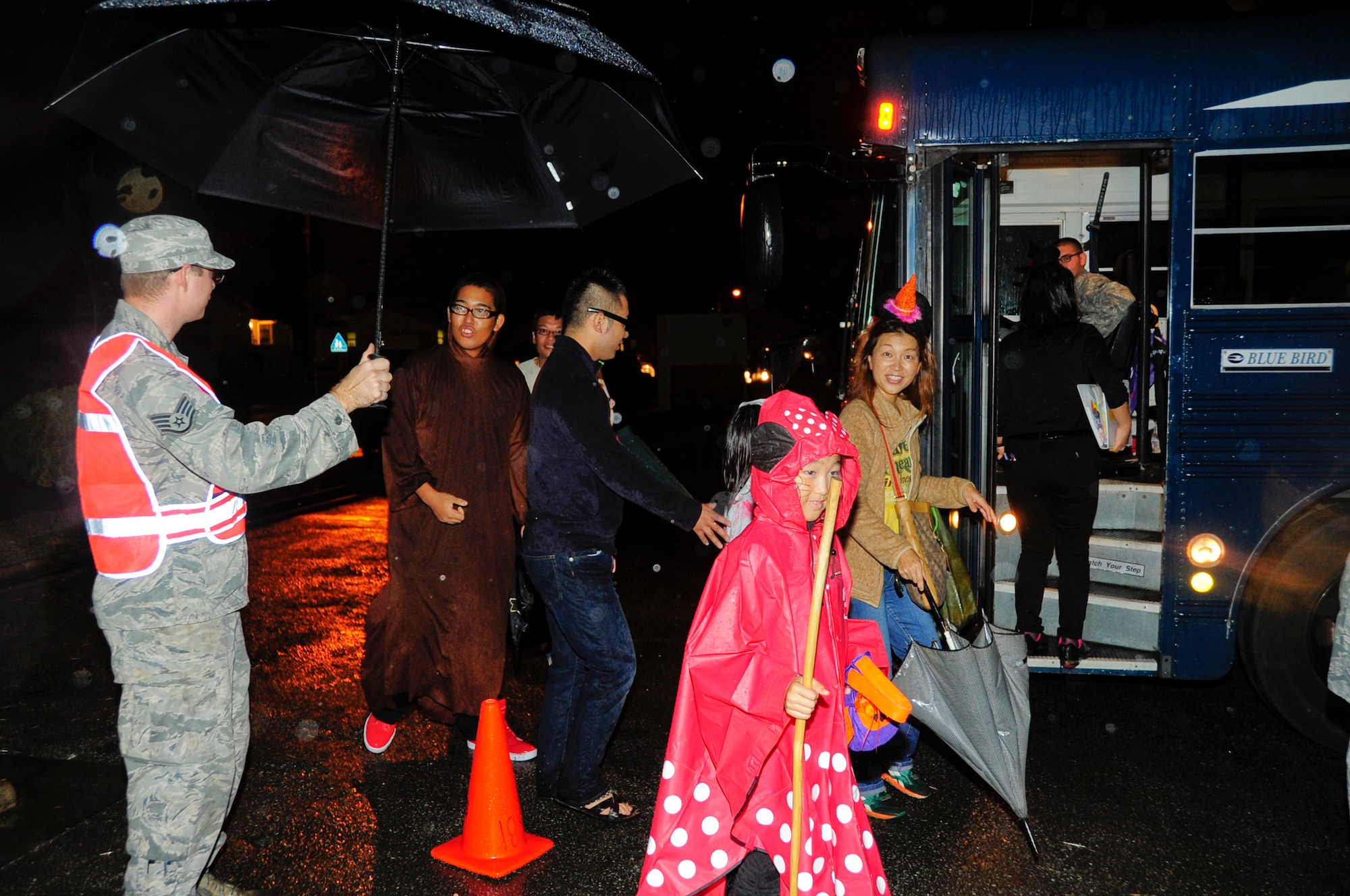 Staff Sgt. Christopher Price, 18th Component Maintenance Squadron aerospace propulsion specialist and Pumpkin Patrol volunteer, holds an umbrella for local national trick-or-treaters during Halloween on Kadena Air Base, Japan, Oct. 31, 2013. Kadena Air Base hosted more than 180 local community members for the Halloween festivities. (U.S. Air Force photo by Staff Sgt. Darnell T. Cannady)