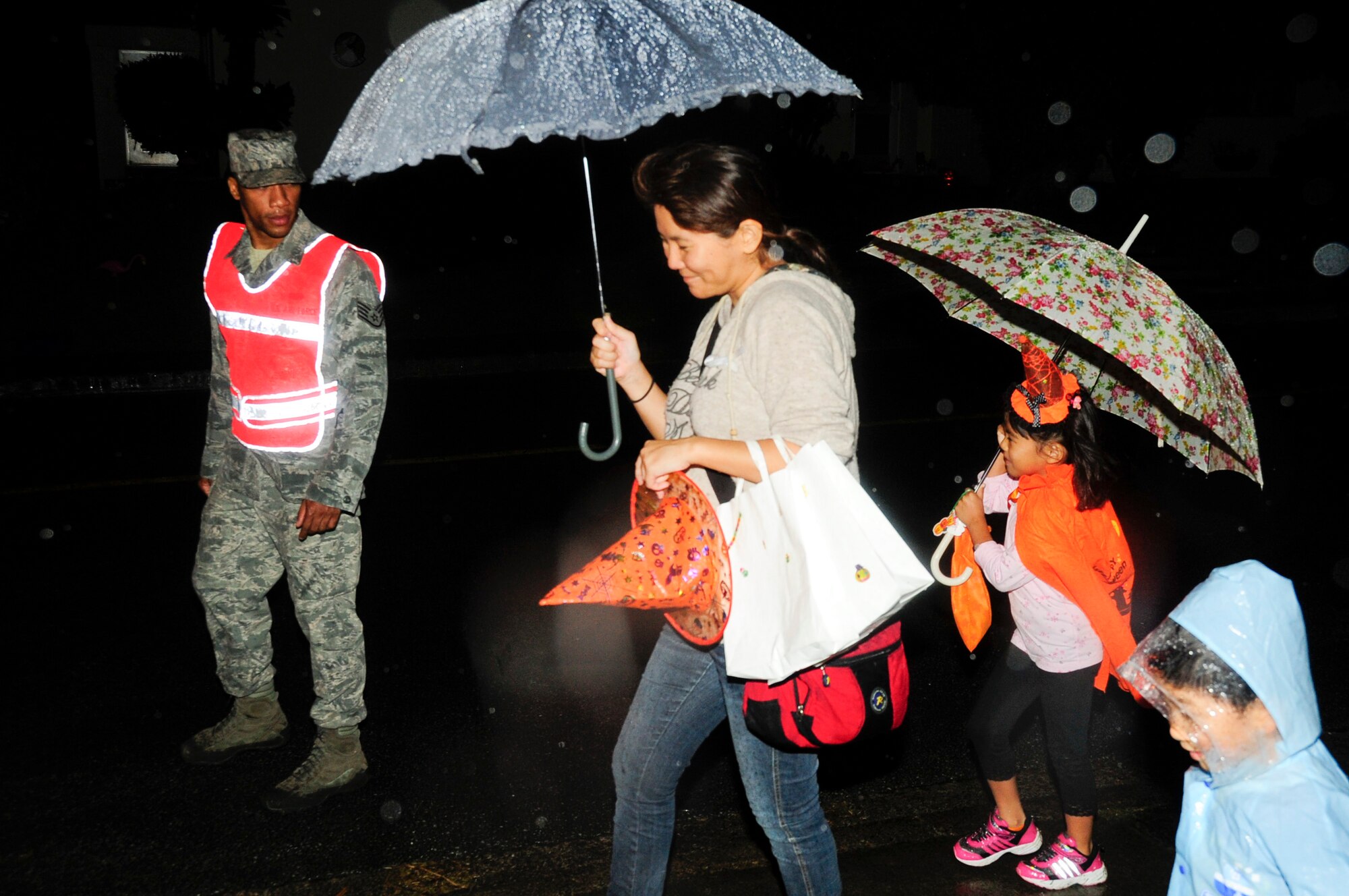 Staff Sgt. Jacques Cabrol, 18th Communications Squadron client systems technician and Pumpkin Patrol volunteer, watches and guides local national trick-or-treaters during Halloween on Kadena Air Base, Japan, Oct. 31, 2013. The Pumpkin Patrol comprised volunteer Airmen from around the base and watched for safety issues and hazards children may encounter as they gather candy. (U.S. Air Force photo by Staff Sgt. Darnell T. Cannady)