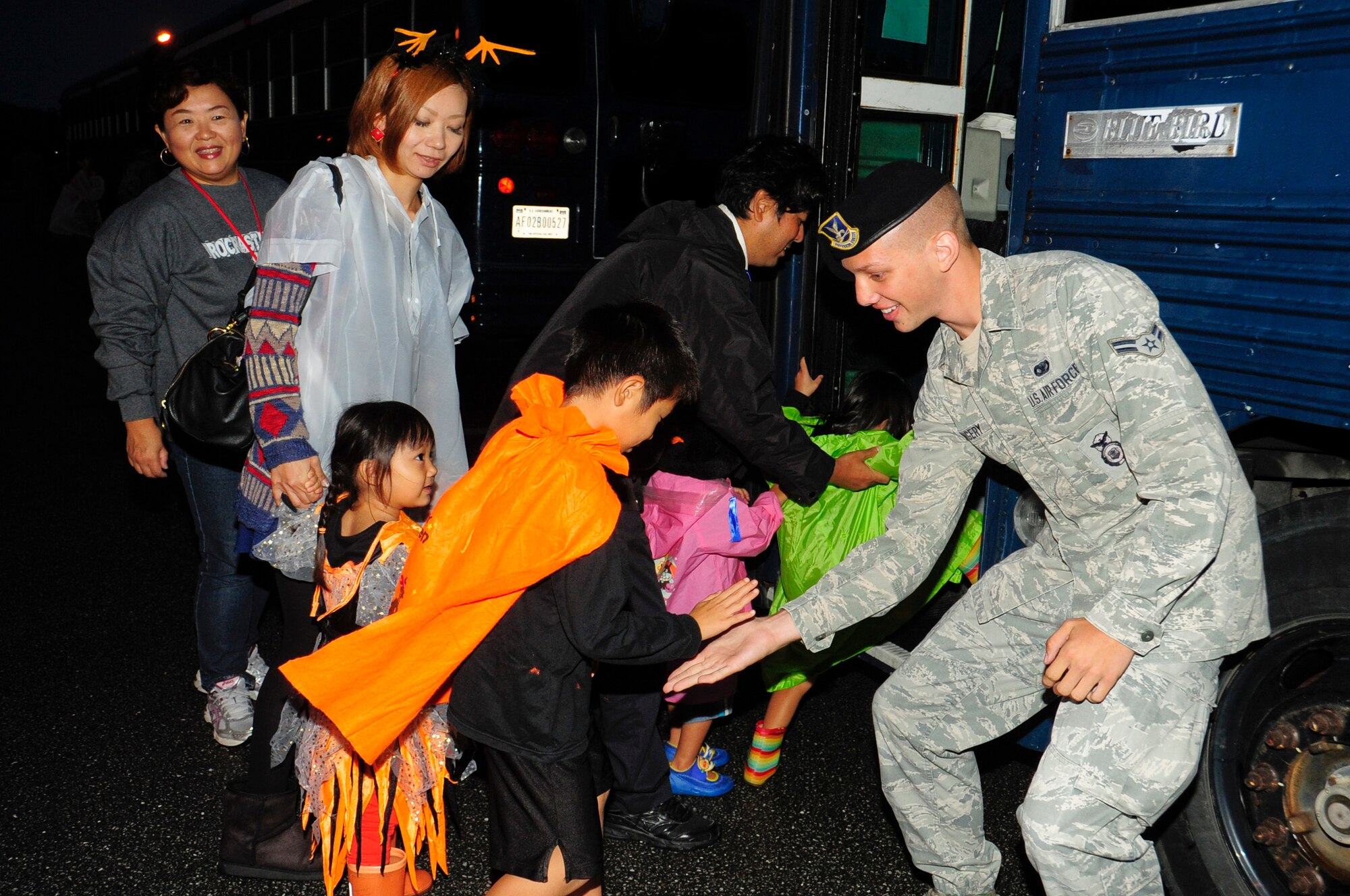 Airman 1st Class Colby Kingery, 18th Security Forces Squadron response force member and escort, greets local nations as they enter buses to begin trick-or-treating on Kadena Air Base, Japan, Oct. 31, 2013. Kadena Air Base bused local families to three base housing areas where they collected candy. The escorts assisted with security and the safety of the trick-or-treaters while they visited the base housing areas. (U.S. Air Force photo by Staff Sgt. Darnell T. Cannady)