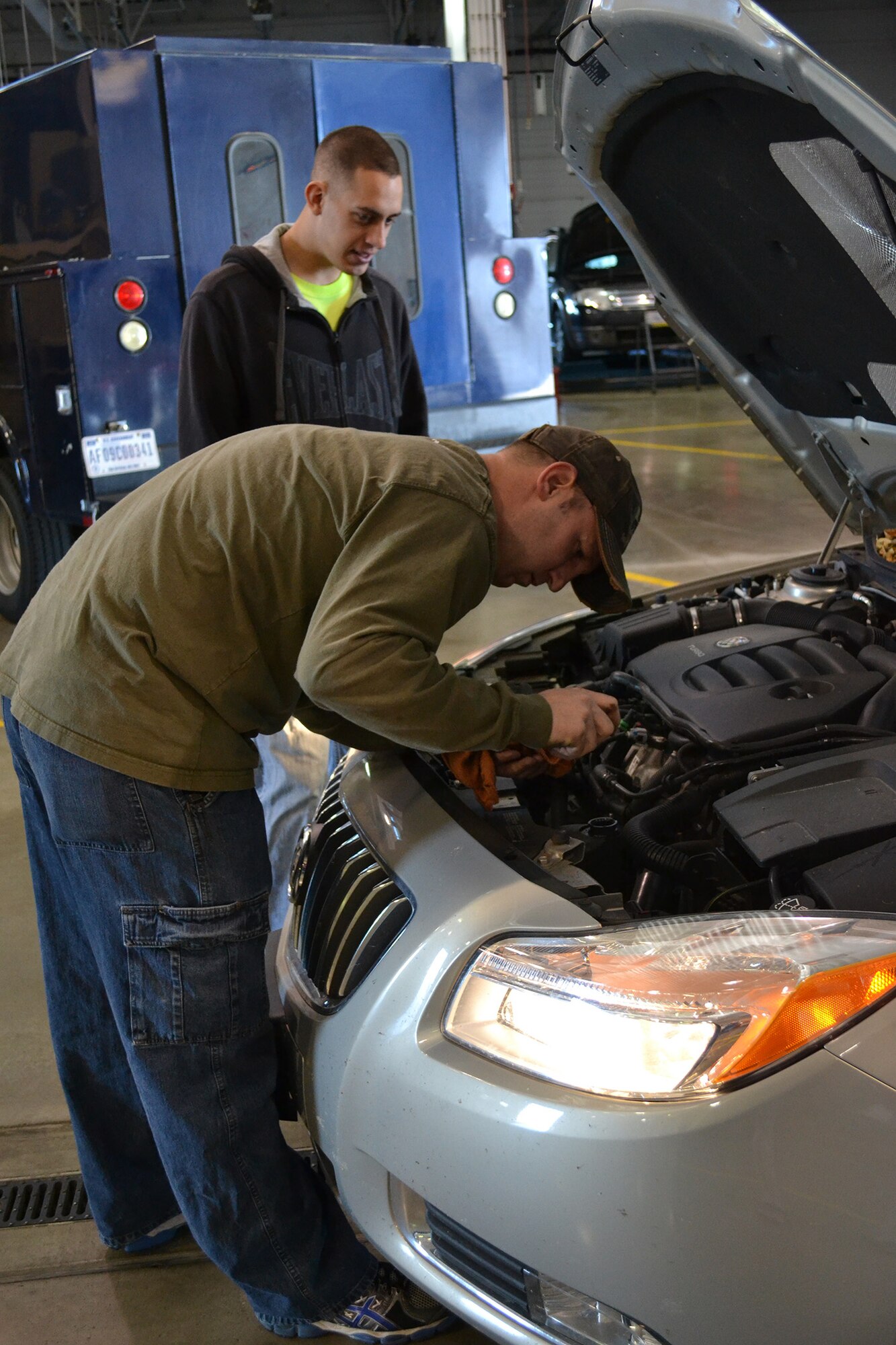 Tech. Sgt. Kevin Pennington, 341st Logistics Readiness Squadron vehicle mechanic (front), checks the fluid levels on a vehicle as Airman 1st Class Zach Simmons, 341st LRS member, watches during the winter personally owned vehicle inspections Oct. 26.  During the free inspections, 341st LRS members checked fluid levels, tire pressure, tire tread, lights, breaks, shocks and mirrors.  (U.S. Air Force photo/Senior Airman Cortney Paxton)