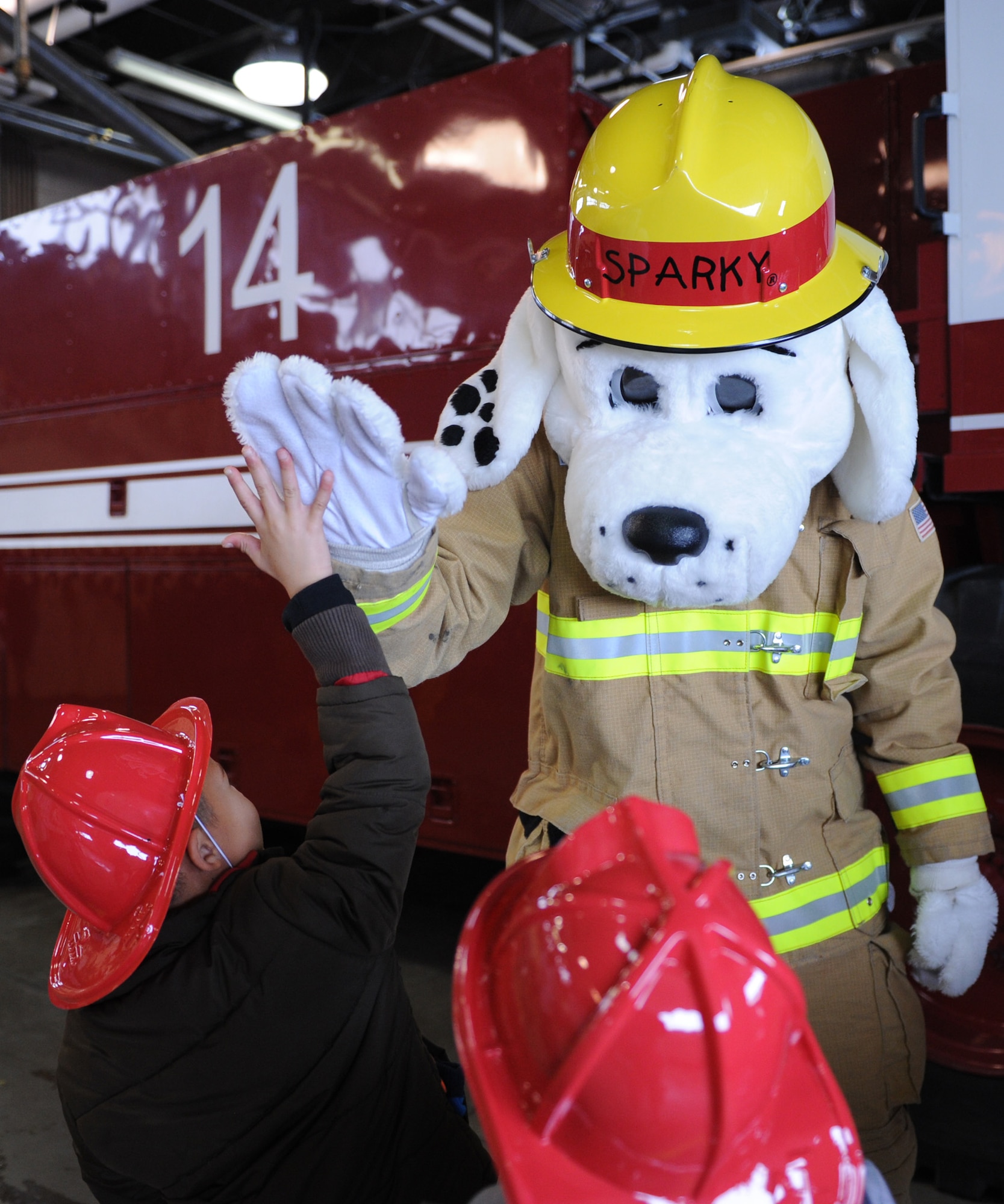 Sparky the Fire Dog high-fives Loy Elementary School kindergarteners after touring the inside of a P-19 Aircraft Rescue Fire Fighting truck named Clifford. The children learned about fire safety and the ins and outs of being a 341st Civil Engineer Squadron fire department member, including a tour of their sleeping barracks, training classroom and dining hall. (U.S. Air Force photo/Senior Airman Katrina Heikkinen)