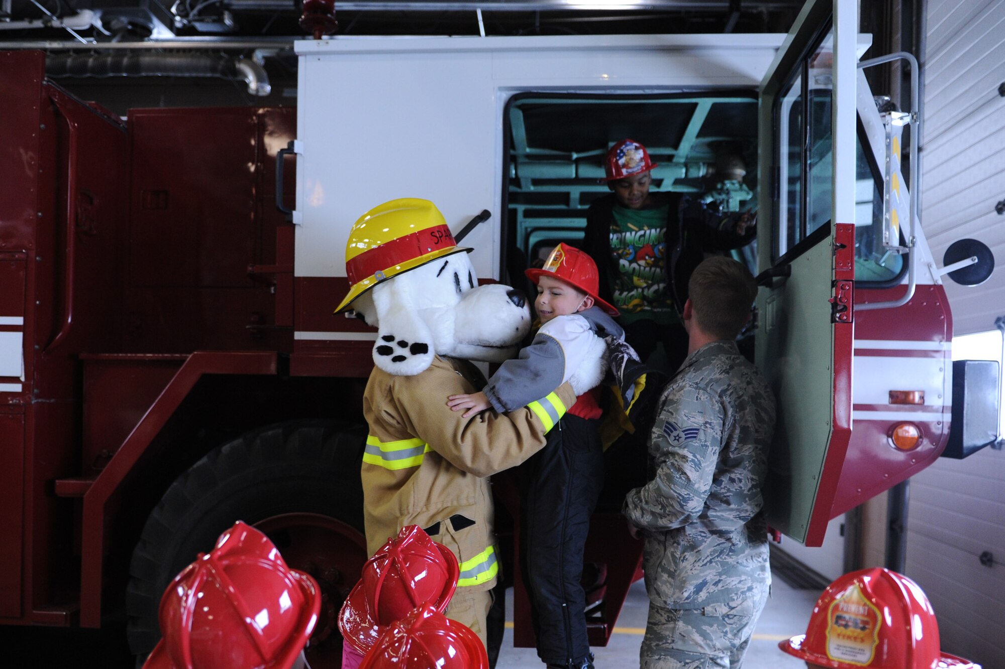 Sparky the Fire Dog and Senior Airman Joshua Grohe, 341st Civil Engineer Squadron firefighter, help children out of a P-19 Aircraft Rescue Fire Fighting truck during a tour of the fire department Oct. 28. More than 50 kindergarteners from Loy Elementary School in Great Falls, Mont., toured the department. (U.S. Air Force photo/Senior Airman Katrina Heikkinen) 
