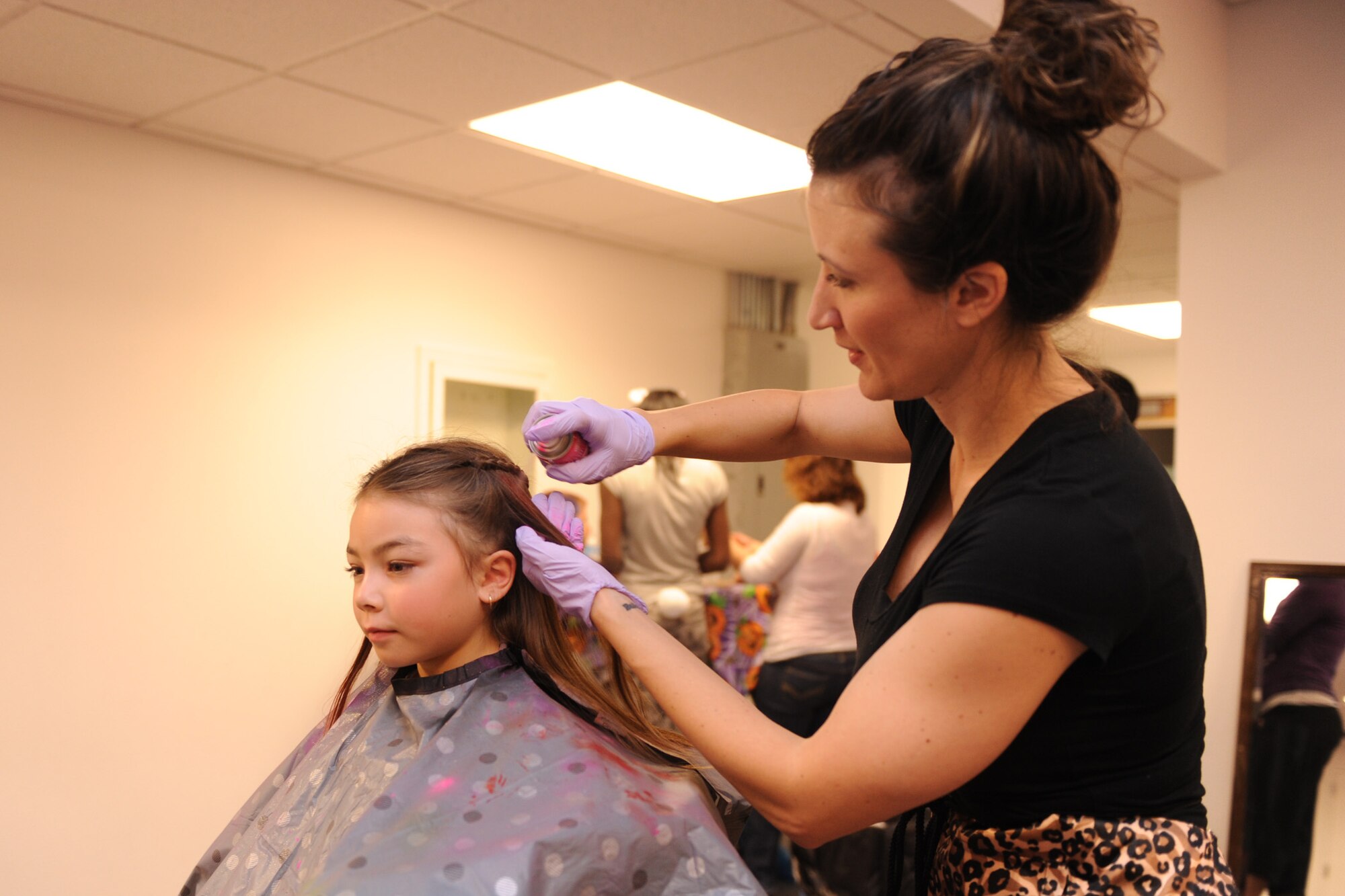 Andrea Gardner, 341st Force Support Squadron school-age coordinator, decorates a girl’s hair with temporary hair color at the Malmstrom Youth Center Fall Festival on Oct. 25. Children who attended the event were entitled to unlimited games and a goody bag. (U.S. Air Force photo/Senior Airman Katrina Heikkinen)