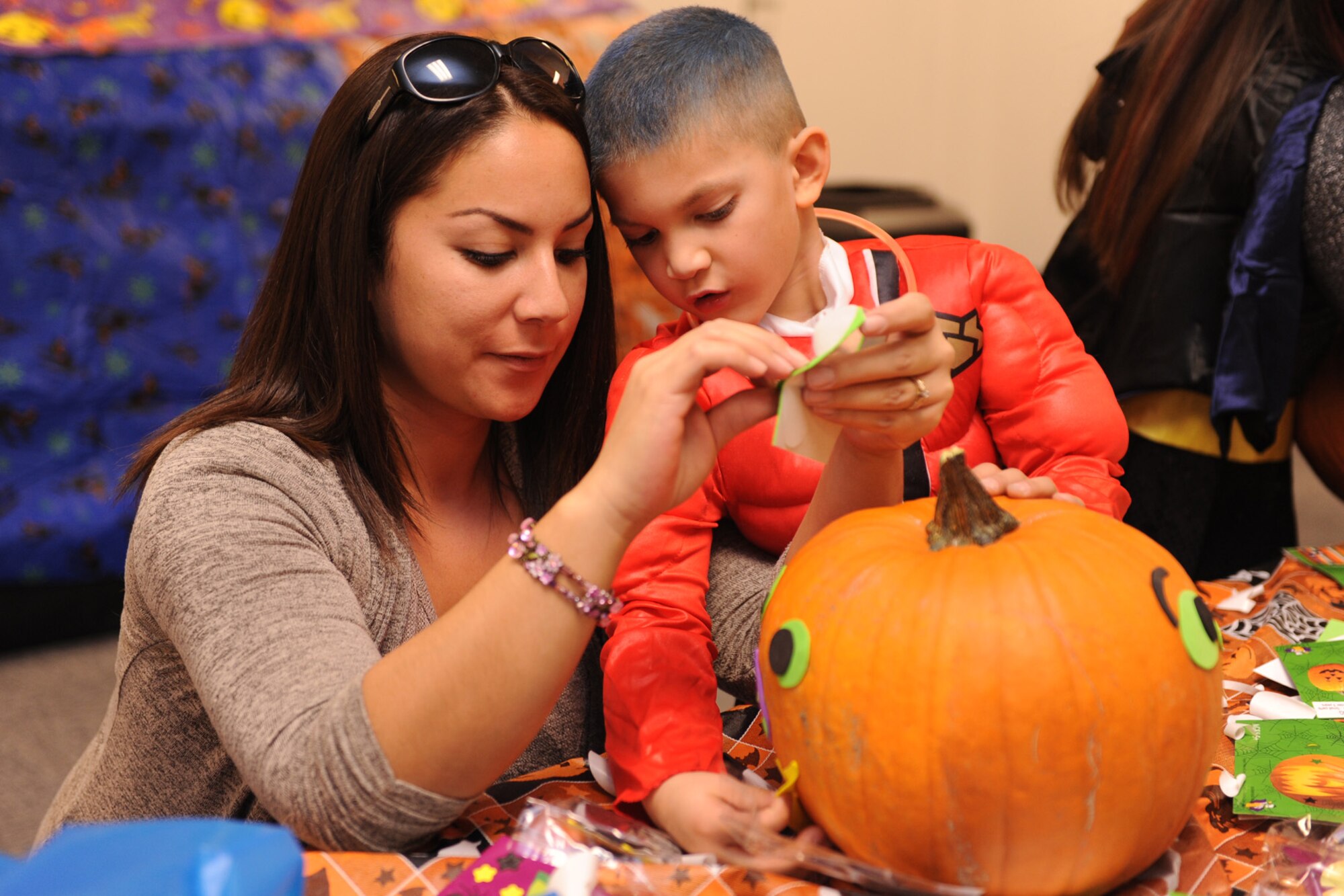 Nicole Lee, spouse of Staff Sgt. Matthew Lee, 819th RED HORSE Squadron member, and her son, Matthew, cover a pumpkin with stickers and various decorations at the pumpkin decorating station during the fall festival. Children and their families enjoyed various games, food and beverages at the annual event. (U.S. Air Force photo/Senior Airman Katrina Heikkinen)