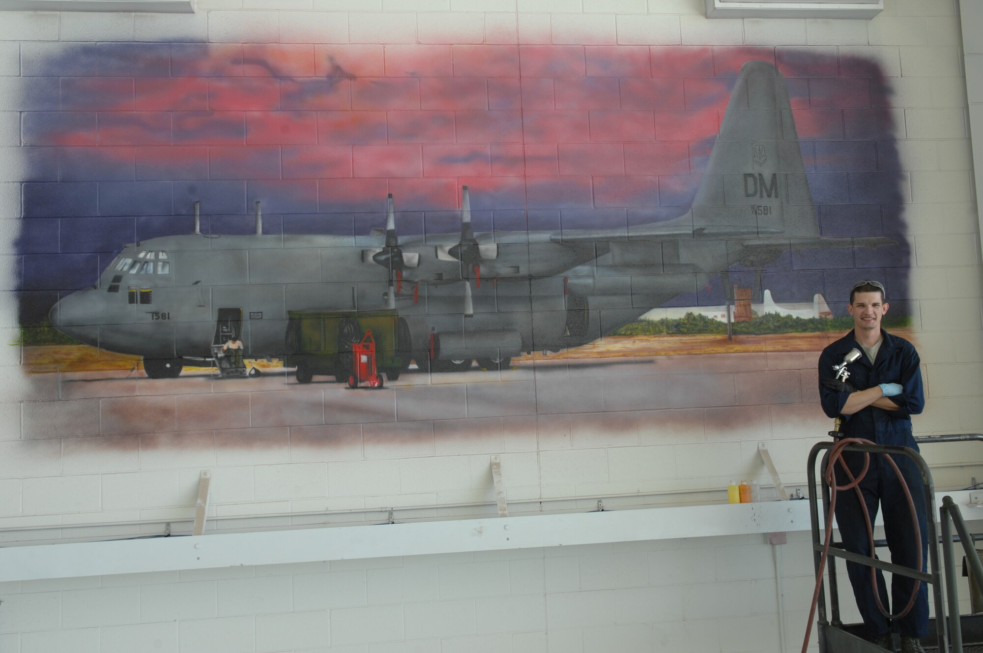 Senior Airman Patrick Corcoran, 755th Aircraft Maintenance Squadron propulsion technician, stands in front of a mural he airbrushed at Davis-Monthan Air Force Base, Ariz., Oct. 17, 2013. The mural took him about six weeks to complete and is the second of five murals be painted in the 755th AMXS hanger. (U.S. Air Force photo by Airman 1st Class Betty R. Chevalier/released)