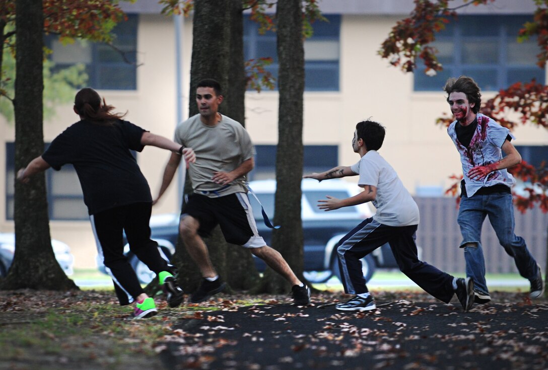 A runner dodges zombies during the Zombie Apocalypse Fun Run and Youth Walk at the MPF track on Joint Base Andrews, Md., Oct. 30, 2013. Runners were given belts with two flags hanging from each side; the object was to complete a mile without the zombies claiming both of your flags. Zombies hid in the trees and waited for the runners to pass by. (U.S. Air Force photo/Senior Airman Lauren Main)