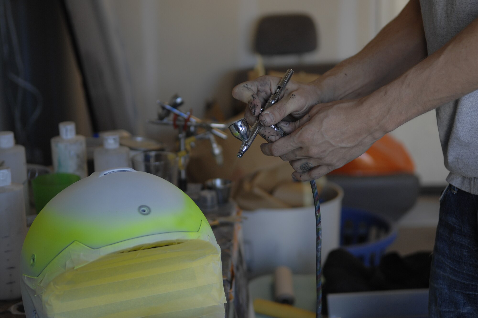 Senior Airman Patrick Corcoran, 755th Aircraft Maintenance Squadron propulsion technician, airbrushes a helmet at Davis-Monthan Air Force Base, Ariz., Oct. 30, 2013. Corcoran uses a neon-colored paint to make guides for tape lines. (U.S. Air Force photo by Airman 1st Class Betty R. Chevalier/released)