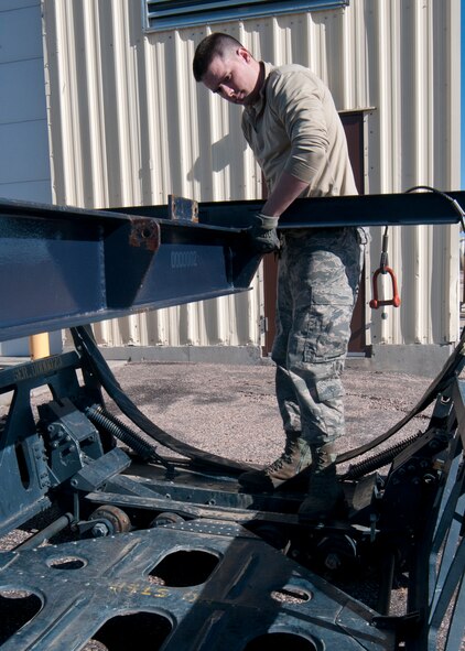 131030-F-BR137-180
Senior Airman Adam Tallman, 90th Missile Maintenance Squadron missile handling technician, removes a tie attaching a forklift to a rocket motor carriage that had just been removed from a transport erector Oct. 30, 2013, in the Missile handling section controlled area on F.E. Warren Air Force Base, Wyo. Once the first carriage was out of the transport erector, the missile handling team removed two more, then re-inserted, or uploaded, them back into the transport to complete their training. (U.S. Air Force photo by Airman 1st Class Jason Wiese)
