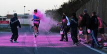 Alex Fryer, running, a Team Mildenhall member from Beck Row, crosses the finish line first at the Color Me Pink run Oct. 30, 2013, near the Hardstand Fitness Center on RAF Mildenhall, England. Service members, civilians and their families participated in the 5km run. In addition to supporting a worthy cause, the run also promoted exercise, healthy competition and esprit de corps. (U.S. Air Force photo by Karen Abeyasekere/Released)