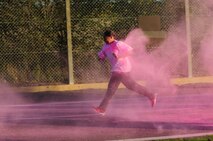 A Team Mildenhall member runs through pink powder at the start of the Color Me Pink run Oct. 30, 2013, in support of Breast Cancer Awareness Month on RAF Mildenhall, England. Service members, civilians and their families participated in the 5km run. More than 50 people participated in the run which supported a worthy cause and promoted high morale. (U.S. Air Force photo by Karen Abeyasekere/Released)