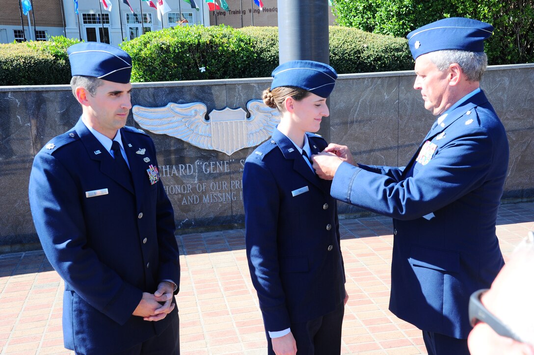 Lt. Col. (Ret.) Steve Ball pins his old pilot wings on his daughter, 2nd Lt. Rebecca Ball as her brother, Lt. Col. Tony Ball, looks on in the Gene Smith Ceremonial Plaza following the SUPT Class 14-01 Graduation. Ball graduated on Friday, October 25 following her father and brother’s footsteps in serving in the Washington Air National Guard first as an enlisted member before receiving her commission and becoming a pilot. Lt. Col. Tony Ball also earned his wings at Columbus Air Force Base as a graduate of class 99-03. (U.S. Air Force Photo/2nd Lt. Cory Concha)