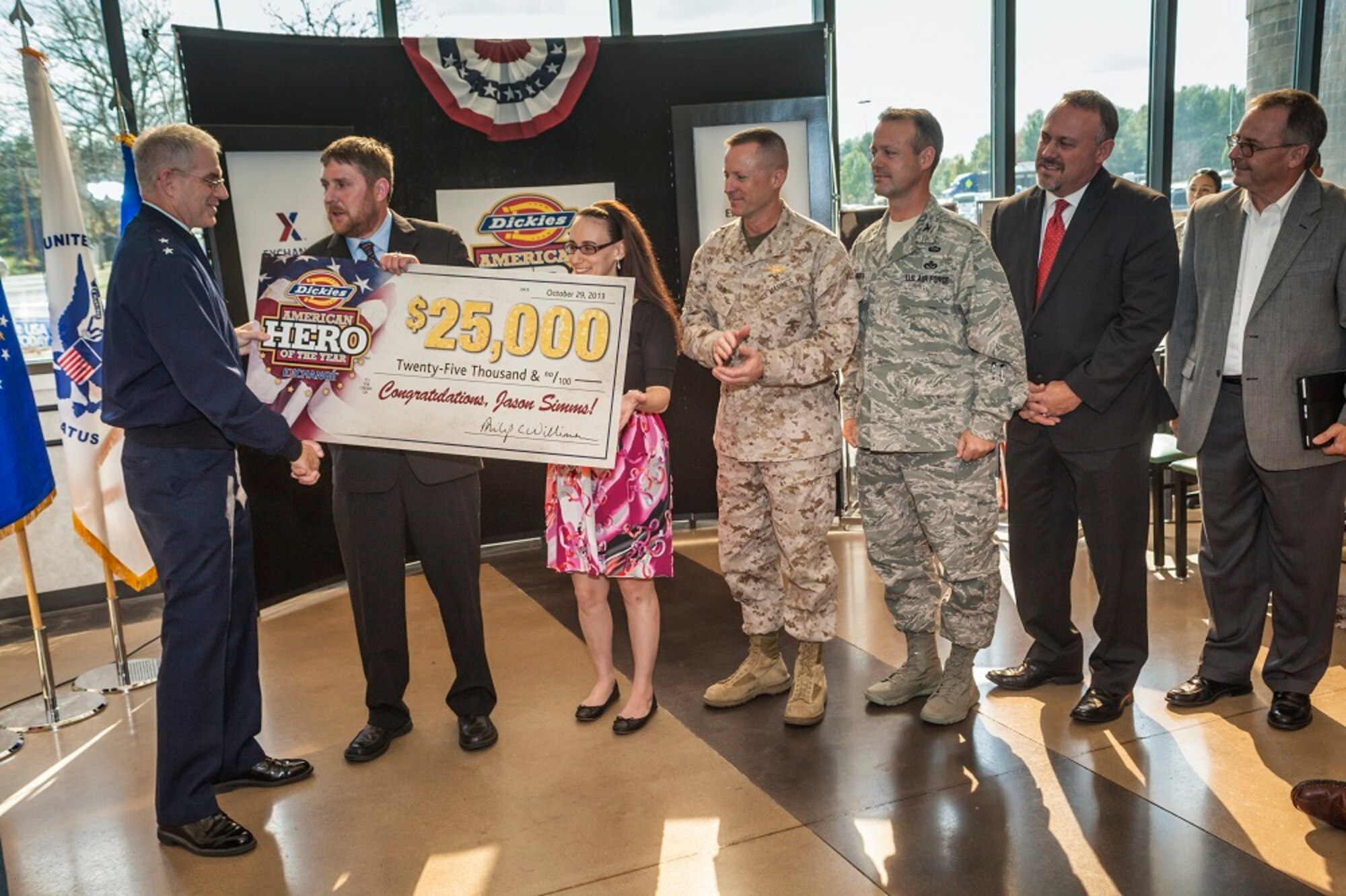 Air Force Maj. Gen. Joseph S. Ward, Army and Air Force Exchange Service deputy director, presents Sgt. Jason Simms with a $25,000 check on behalf of Dickies and AAFES as the 2013 Dickies American Hero of the Year Oct. 29, 2013, at the Exchange at Joint Base McGuire-Dix-Lakehurst, N.J. His wife, Alana Simms, nominated him for his courage and heroism he exhibits by working with the Navy' Human Resource Service Center and the Wounded Warrior Project to help injured veterans like himself find employment after they return from service. (U.S. Air Force photo by Wayne Russell/Released)
