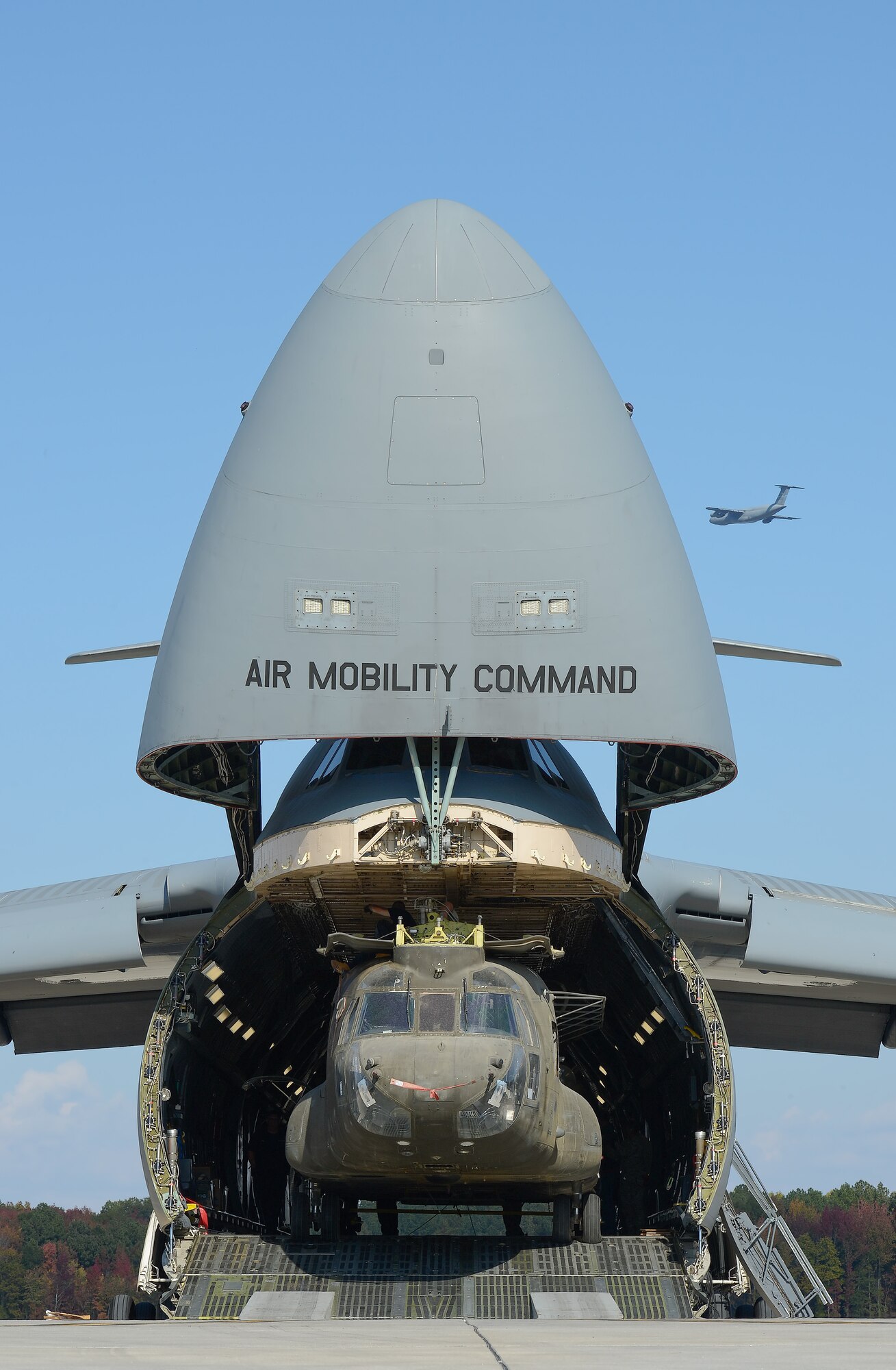 United States Army CH-47D Chinook helicopters and their components are unloaded from a C-5M Super Galaxy of the 436th Airlift Wing, Oct. 29, 2013, Dover Air Force Base, Del. Another C-5M can be seen in the background conducting a training flight. The helicopters were used in Afghanistan and are being returned to the United States as military forces are withdrawn from the country. (U.S. Air Force photo/Greg L. Davis)