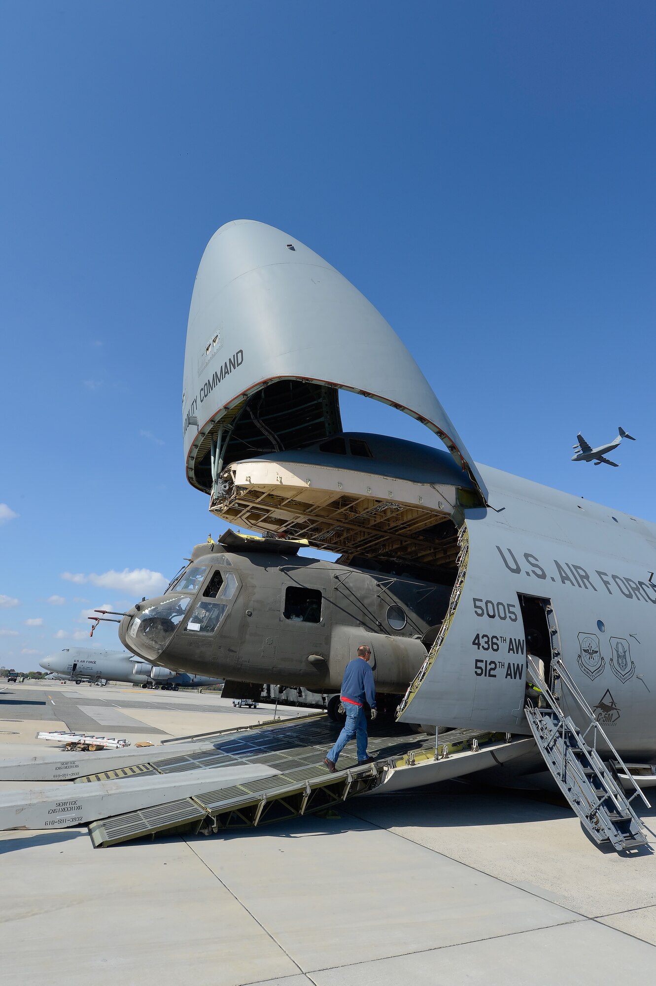 United States Army CH-47D Chinook helicopters and their components are unloaded from a C-5M Super Galaxy of the 436th Airlift Wing, on Oct. 29, 2013, Dover Air Force Base, Del.  The helicopters were used in Afghanistan and are being returned to the United States as military forces are withdrawn from the country. A C-17A Globemaster III, also from the 436th AW, can be seen flying overhead. (U.S. Air Force photo/Greg L. Davis)