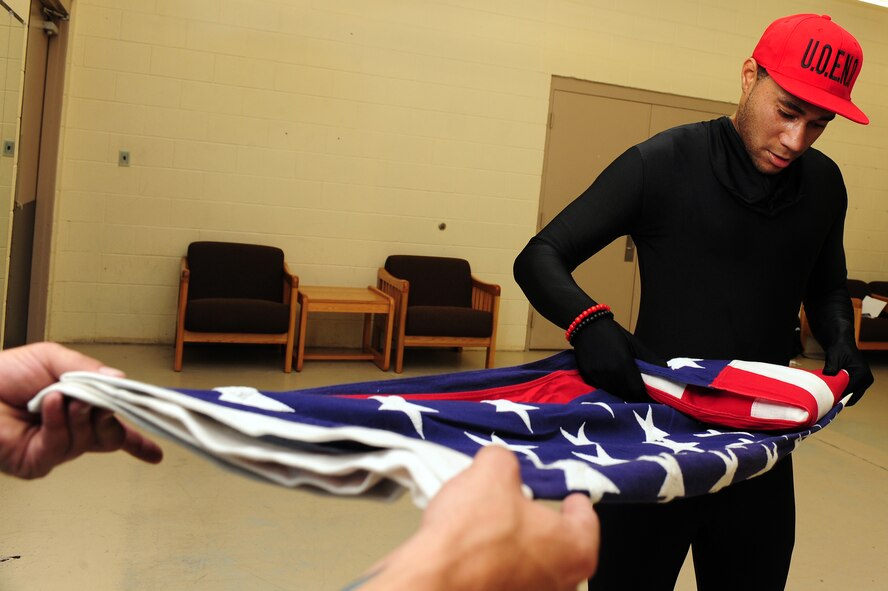 U.S. Air Force Senior Airman Reginald Graves, 4th Component Maintenance Squadron precision measurement equipment laboratory technician, folds an American flag during the Community Quest Game of Discovery at Seymour Johnson Air Force Base, N.C., Oct. 25, 2013. The Game of Discovery was a base-wide scavenger hunt where teams raced against the clock to complete 10 challenges. (U.S. Air Force photo by Airman 1st Class John Nieves Camacho)