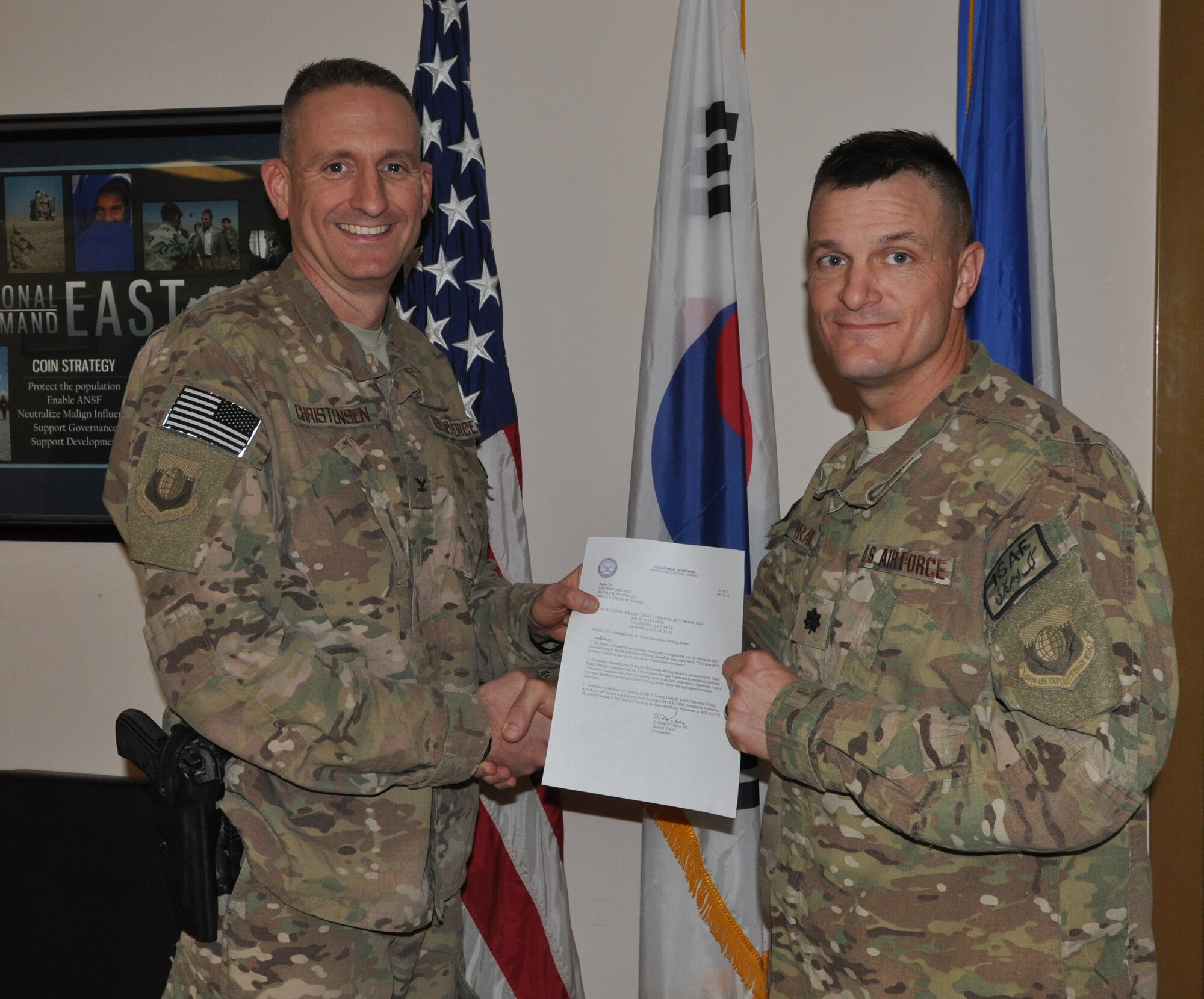 Col. Glen Christensen, 455th Expeditionary Base Defense Group commander, deployed from Joint Base San Antonio Lackland, Texas, and a native of Madelia, Minn., presents a congratulatory memorandum from U.S. Air Force Gen. C. Robert Kehler, U.S. Strategic Command commander, to Lt. Col. Seth Frank, 755th Expeditionary Security Forces Squadron commander, who’s assigned to the Pentagon, Washington, D.C., and a native of California, Mo., for winning the 2013 Gen. Larry D. Welch Deterrence Writing Award at Bagram Airfield, Afghanistan, Oct. 28, 2013. (U.S. Air Force photo/Tech. Sgt. Rob Hazelett)
