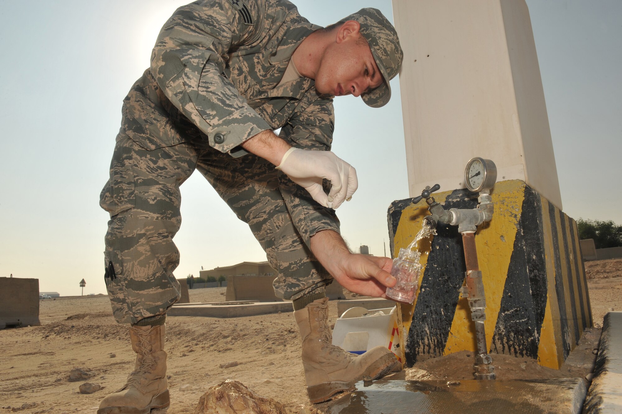Senior Airman Dustyn White collects a water sample at the Lima Gate entry point at the 379th Air Expeditionary Wing in Southwest Asia, Oct. 27, 2013. The water entering the base is tested for pH, chlorine, total coliform and fecal coliform. White is the 379th Expeditionary Medical Group Bioenvironmental Engineering environmental quality program manager deployed from Holloman Air Force Base, N.M., and a Porterville, Calif., native. (U.S. Air Force photo/Master Sgt. David Miller)