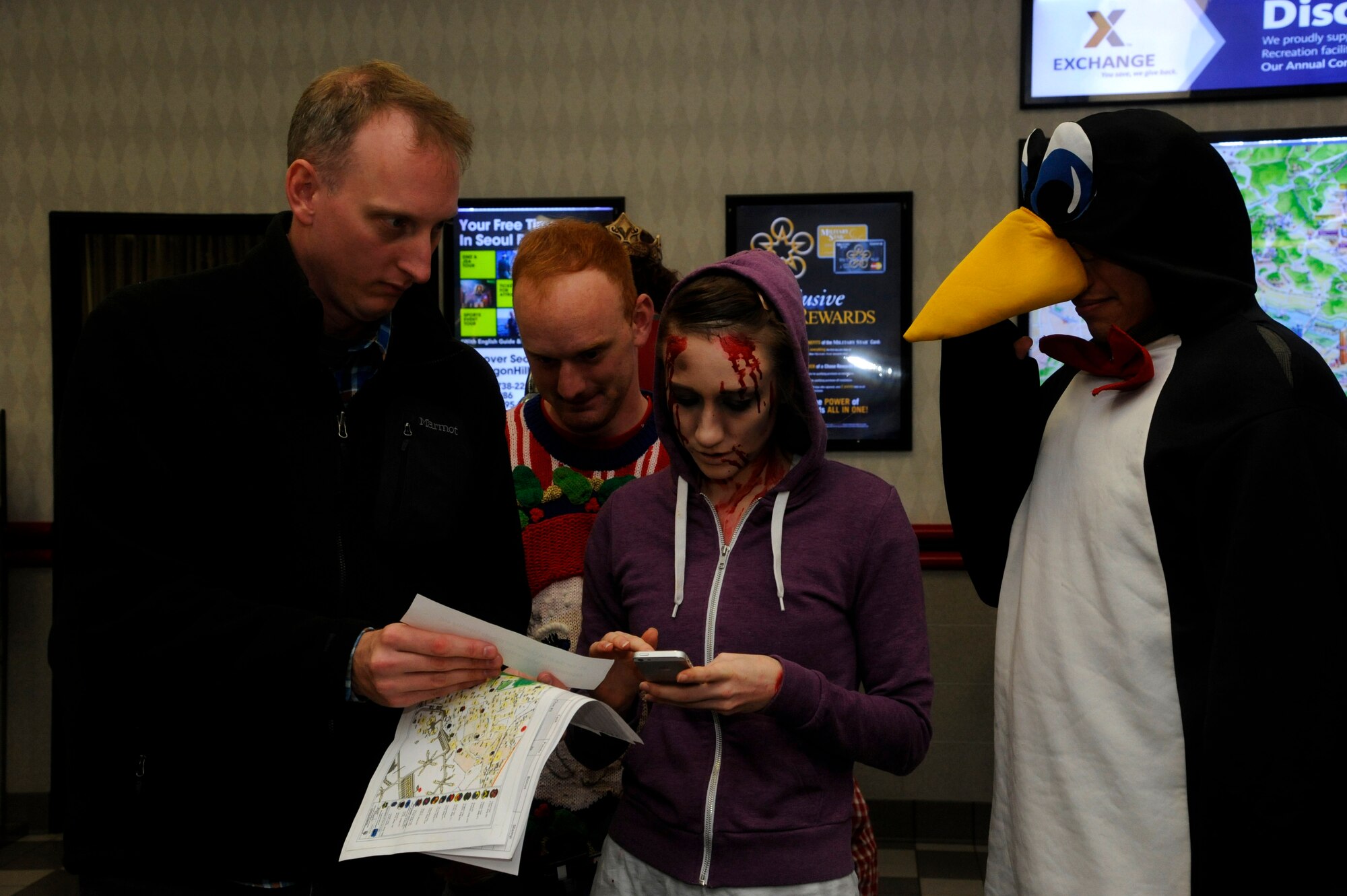 The Public Affairs team reads a trivia question at the Exchange at Kunsan Air Base, Republic of Korea, Oct. 26, 2013 as part of the Top 3 sponsored Halloween Scavenger Hunt. . To win the hunt, teams were required to travel to a variety of locations throughout base, answer Kunsan and Squadron heritage questions and take photographs.  Each task completed was worth points. (U.S. Air Force photo by Staff Sgt. Jessica Haas/Released)