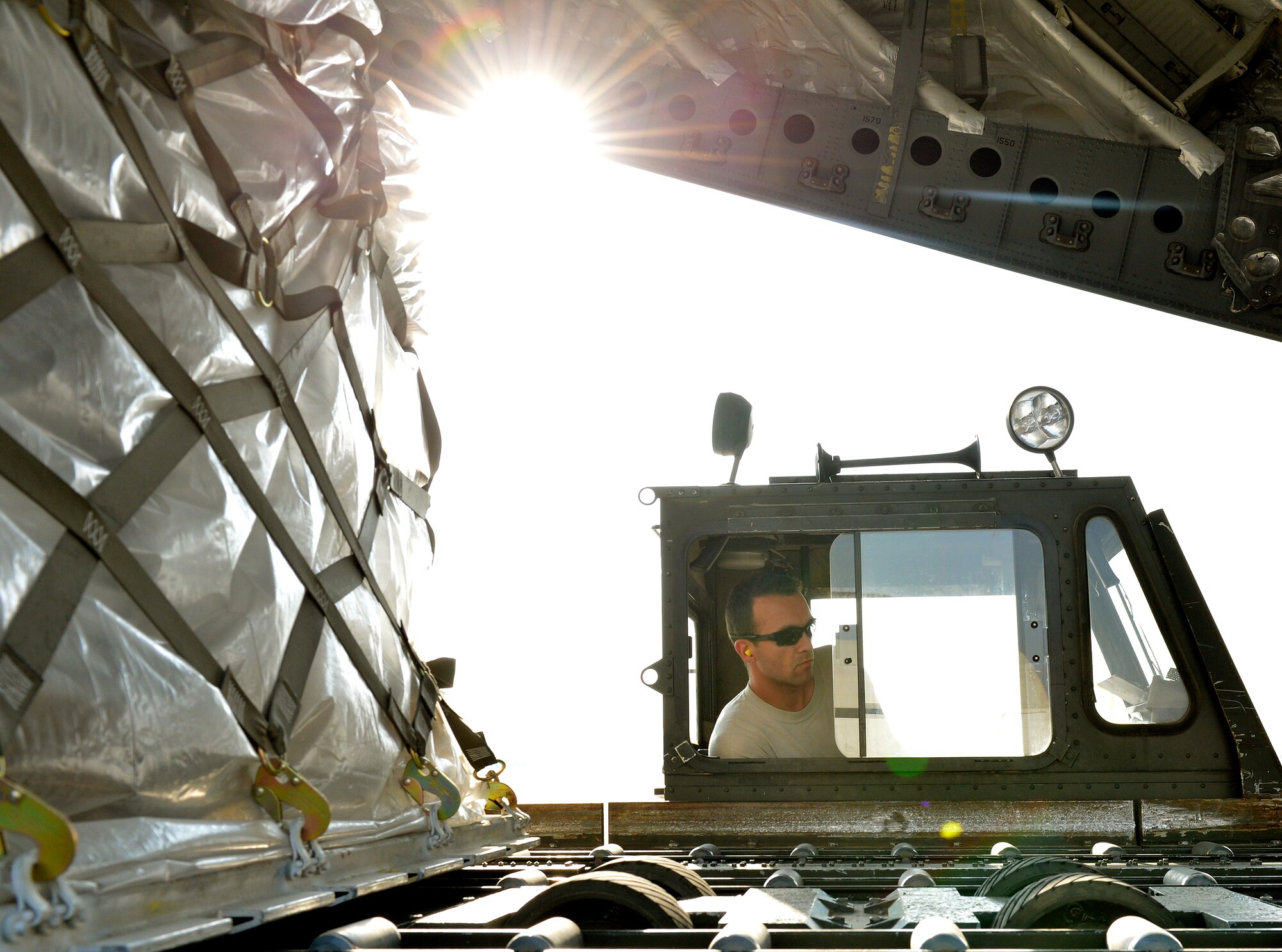 Staff Sgt. Garrett Ingram 455th aerial port specialist drives a K-loader up to a C-17 with the help from a loadmaster on Forward Operating Base Mazar-E-Sharif, Afghanistan. The K-loader will be used to offload cargo pallets. He is deployed from Davis Monthan Air Force Base, Ariz., and native of San Marcus, Calif. (U.S. Air Force photo/Staff Sgt. Stephenie Wade)