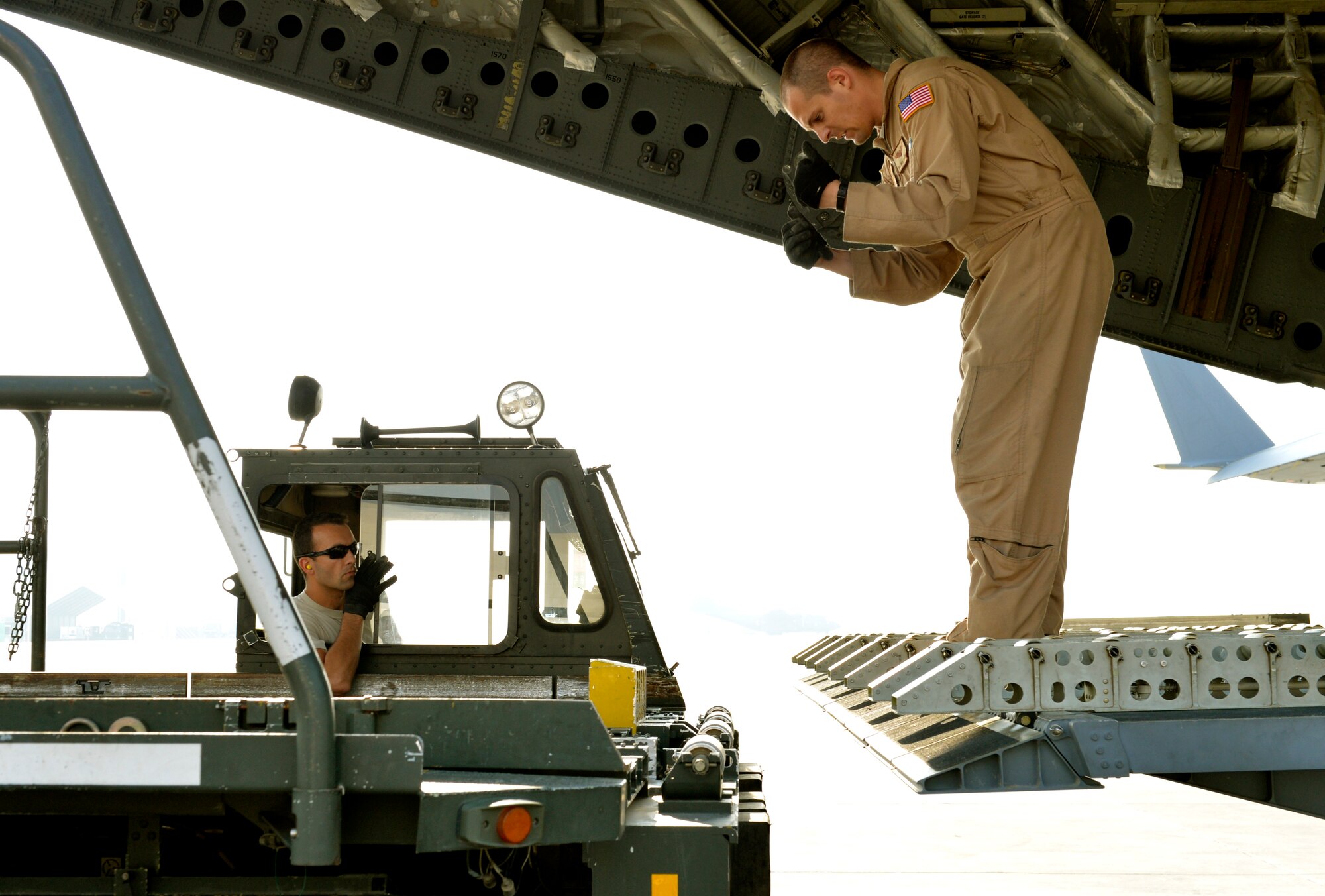 (left) Staff Sgt. Garrett Ingram 455th aerial port specialist drives a K-loader up to a C-17 with the help from a loadmaster on Forward Operating Base Mazar-E-Sharif, Afghanistan. The K-loader will be used to offload cargo pallets. He is deployed from Davis Monthan Air Force Base, Ariz., and native of San Marcus, Calif. (U.S. Air Force photo/Staff Sgt. Stephenie Wade)