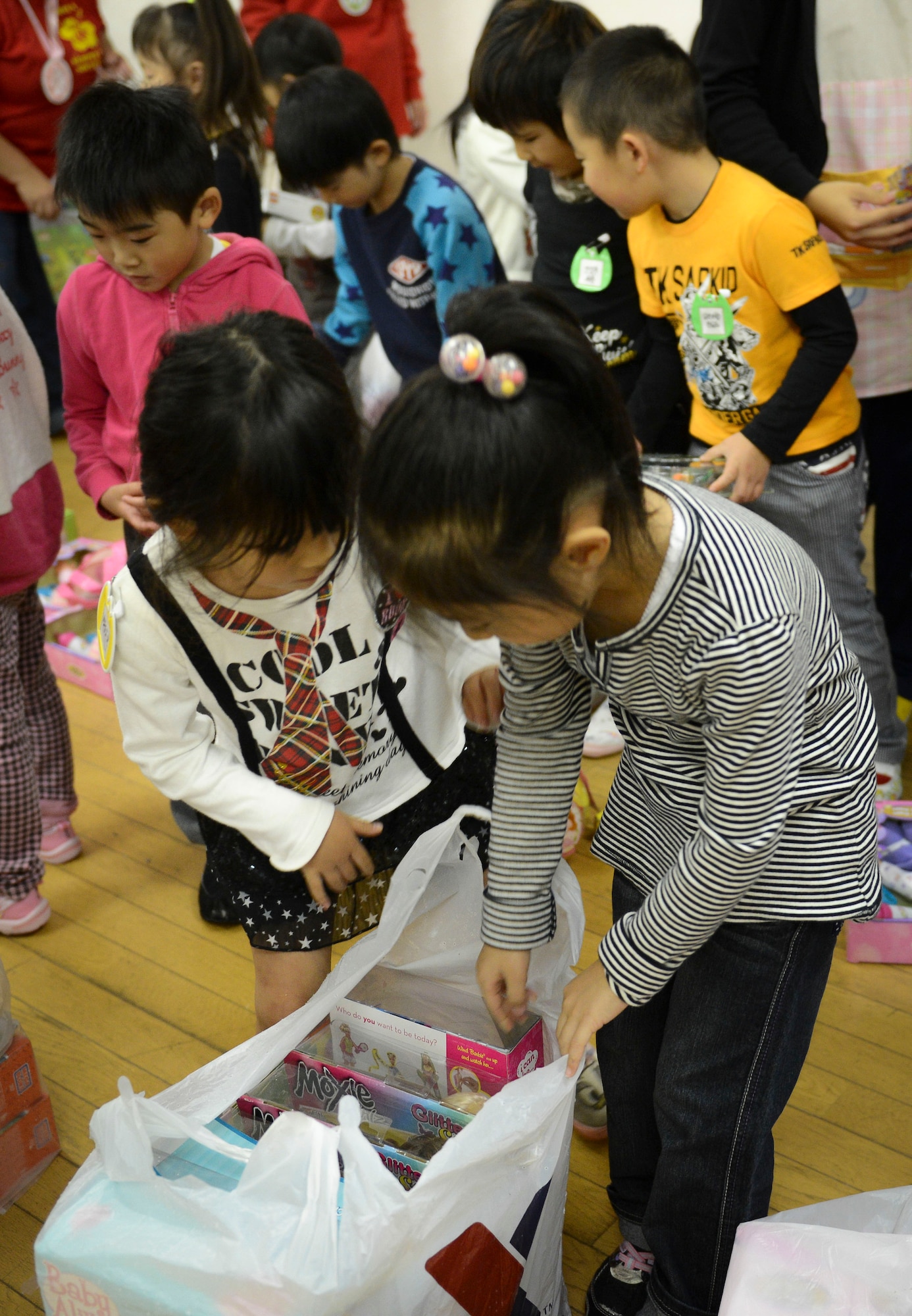 Two girls look to see what gifts are inside a bag at Kaminakajima preschool in Kamaishi-shi, Japan, Oct. 25, 2013.  Baby dolls, stuffed animals, Legos and more were some of the toys donated from the Semper Fi Society. (U.S. Air Force photo by Airman 1st Class Meagan Schutter/Released)