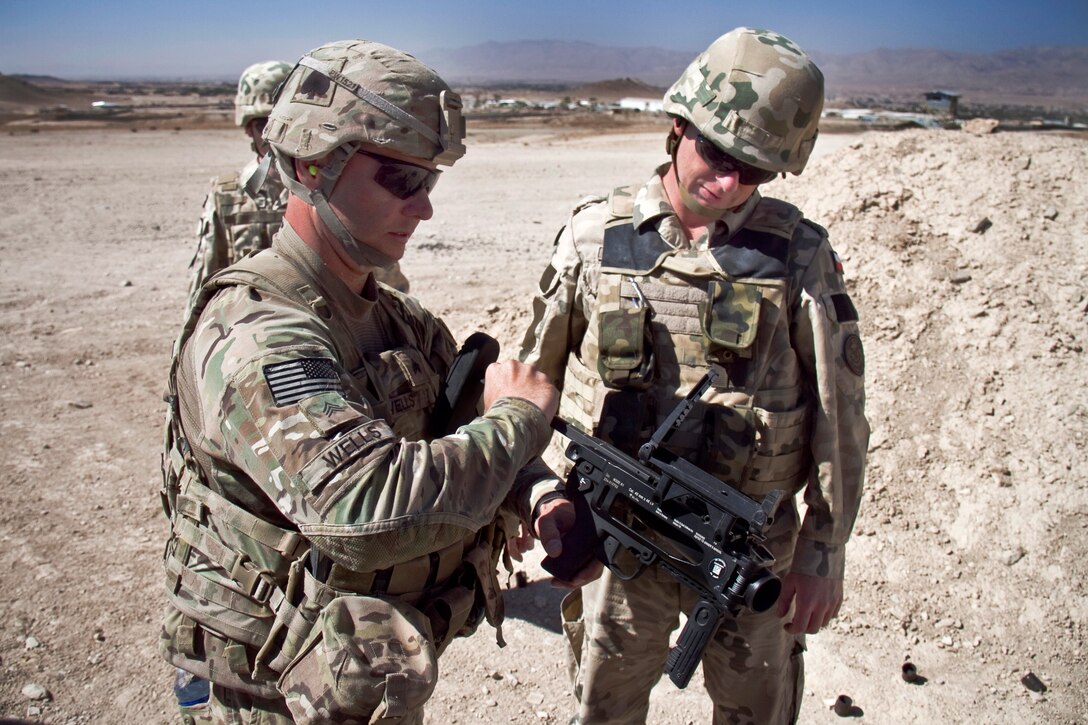 U.S. Army Sgt. Paul G. Wells, left, shows a Polish soldier how to ...