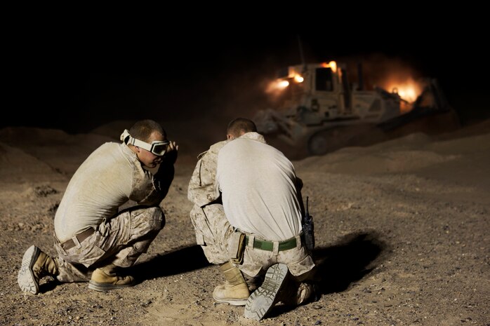 Two combat engineers with Combat Logistics Regiment 2, Regional Command (Southwest), discuss methods for erecting a new guard tower at Camp Dwyer, Afghanistan, Aug. 12, 2013. A platoon of combat engineers and heavy equipment operators worked through the night and endured the constant sting of blowing sand to erect a new guard tower at the base.