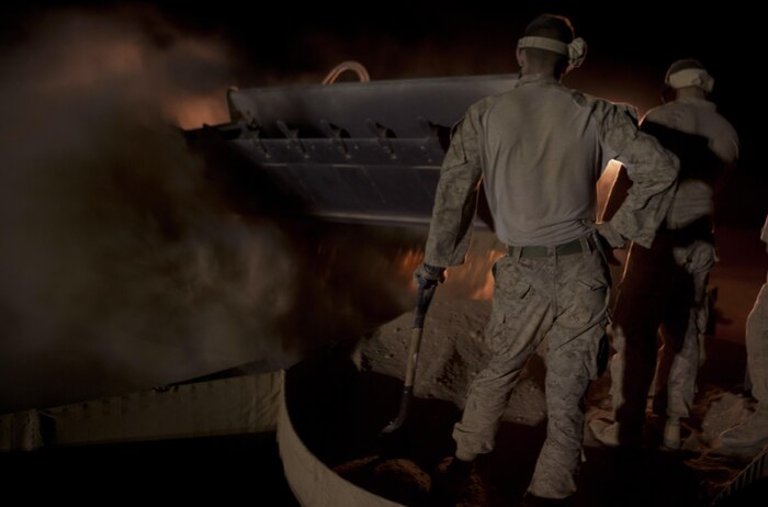 Two combat engineers with Combat Logistics Regiment 2, Regional Command (Southwest), stand on HESCO containers as a tram dumps a load of sand at Camp Dwyer, Afghanistan, Aug. 12, 2013. A platoon of combat engineers and heavy equipment operators worked through the night and endured the constant sting of blowing sand to erect a new guard tower at the base.