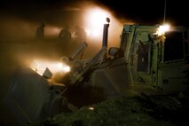 Combat engineers with Combat Logistics Regiment 2, Regional Command (Southwest), work on HESCO containers as a bulldozer levels the area for a new guard tower at Camp Dwyer, Afghanistan, Aug. 12, 2013. A platoon of combat engineers and heavy equipment operators worked through the night and endured the constant sting of blowing sand to erect a new guard tower at the base.