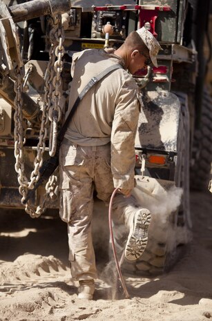 Lance Cpl. Dylan Freed, an Alma, Mich., native and vehicle recovery operator with Combat Logistics Regiment 2, Regional Command (Southwest), hoses flour-like sand off his uniform at Combat Outpost Erdevi in Helmand province, Afghanistan, Aug. 22, 2013. The fine sand rose to ankle height and filled the air as vehicles moved around the outpost.