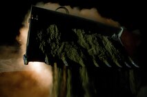 A looming tram bucket dumps a load of sand into empty HESCO containers at Camp Dwyer, Afghanistan, Aug. 13, 2013. Marines with Combat Logistics Regiment 2, Regional Command (Southwest), worked through the night and endured the constant sting of blowing sand to erect a new guard tower at the base.