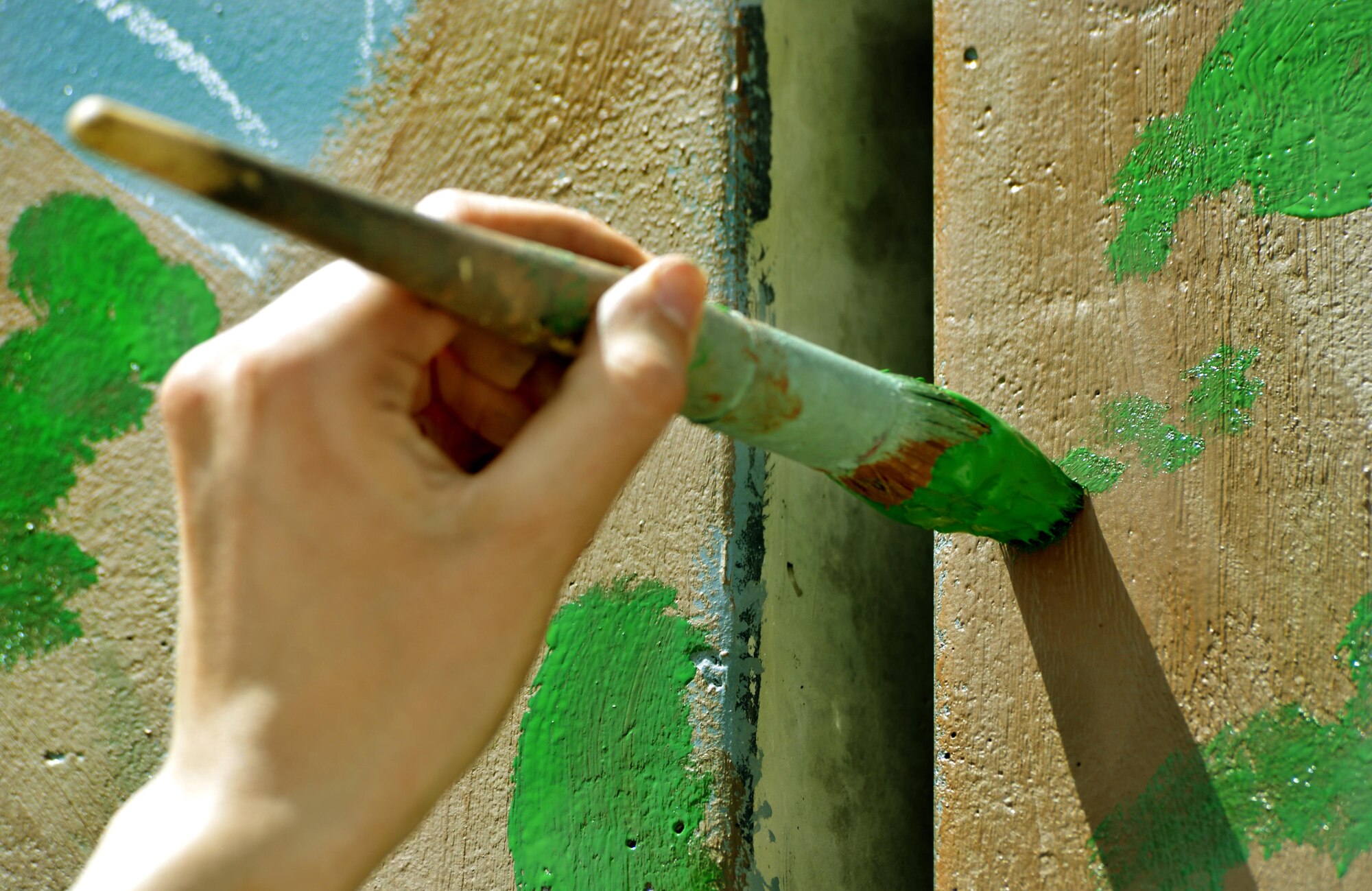 An airman paints her interpretation of unity, respect, trust, strength and the will to protect on a wall leaving a visual legacy for those who follow in their footsteps to see here on Camp Cunningham Aug. 30, 2013. (U.S. Air Force photo/Staff Sgt. Stephenie Wade)