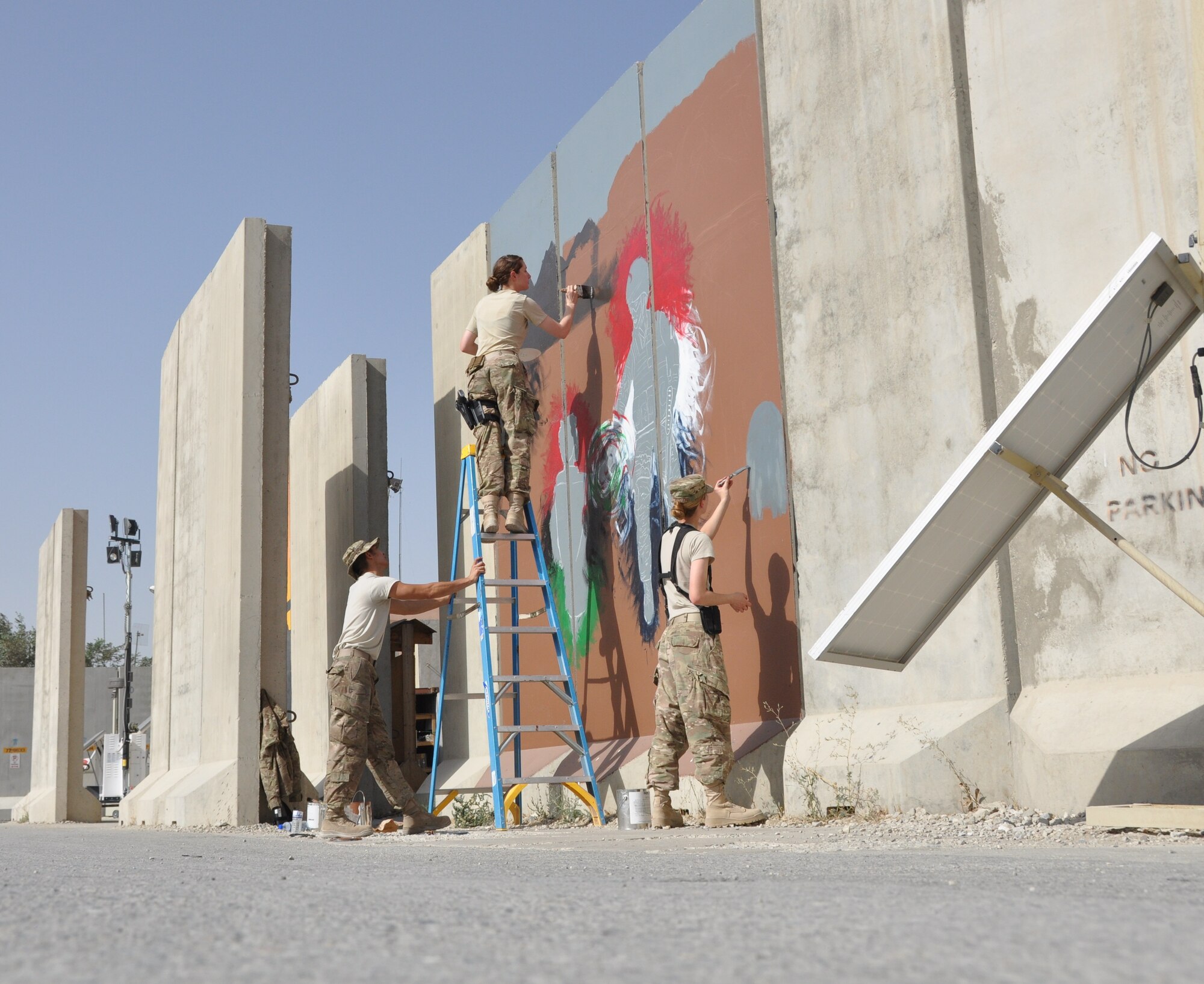 Airman 1st Class Eli Hixson, 455th Expeditionary Aerial Port Squadron air transportation passenger service agent, Senior Airman Brittney Snyder, 455th Air Expeditionary Wing personnel support, and Senior Airman Alyona Blizard, 455th Expeditionary Communications Squadron communications focal point technician, painted their interpretation of unity, respect, trust, strength and the will to protect on a wall leaving a visual legacy for those who follow in their footsteps to see here on Camp Cunningham Aug. 30, 2013. (U.S. Air Force photo/Tech. Sgt. Rob Hazelett)