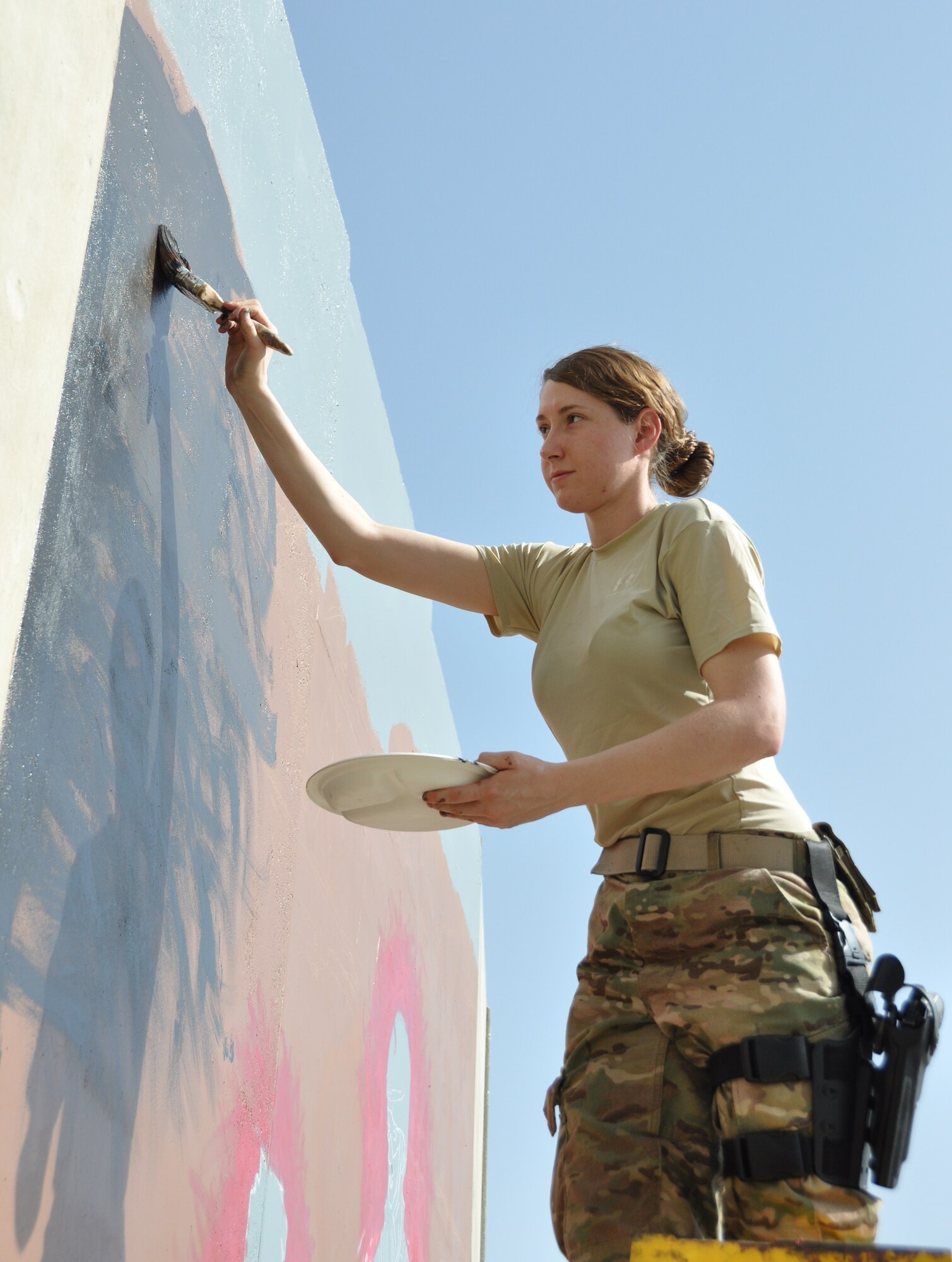 Senior Airman Brittney Snyder, 455th Air Expeditionary Wing personnel support, paints a mural depicting the bonds, unity, respect, trust, strength and the will to protect on the walls on Bagram Airfield, Afghanistan, Aug. 30, 2013. “We are showing the unity of two cultures coming together,” said Snyder, deployed from Joint Base Langley-Eustis, Va., and a three-year Air Force veteran proudly hailing from Ocean Springs, Miss. “Although we are from different countries we are building relationships to protect the innocent.” (U.S. Air Force photo/Tech. Sgt. Rob Hazelett)