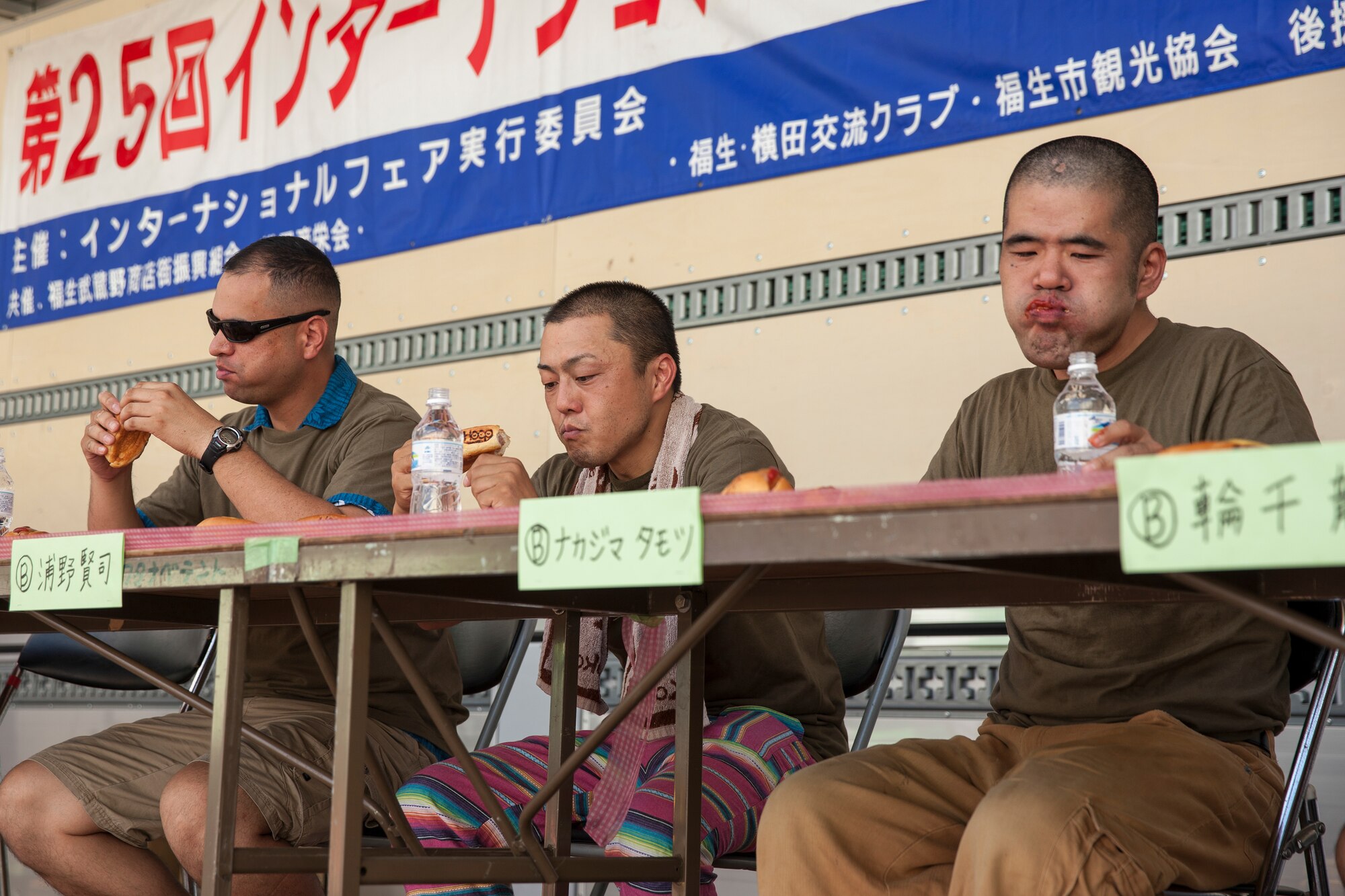 Master Sgt. Brandon Kirkham, left, 374th Maintenance Squadron, participates in the hot dog eating competition during the 25th annual Fussa City International Fair, Aug. 31, 2013. Yokota Airmen participated in many unique events, included music, food, and parade. (U.S. Air Force photo by Osakabe Yasuo/Released)