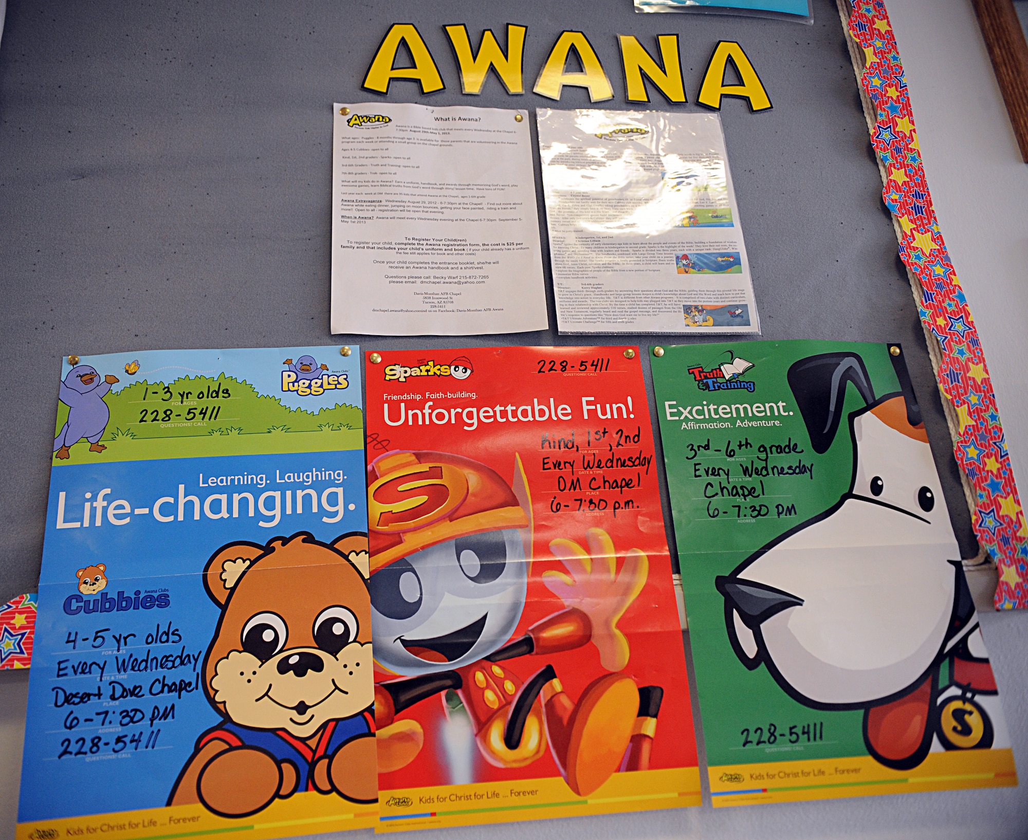Posters with information about the Awana program hang on a display board in the chapel at Davis-Monthan Air Force Base, Ariz., Aug. 29, 2013. The program meets every Wednesday between September 2013 and May 2014, excluding holidays, and is open to dependents of service members and DoD employees. (U.S. Air Force photo by Senior Airman Timothy Moore/Released)