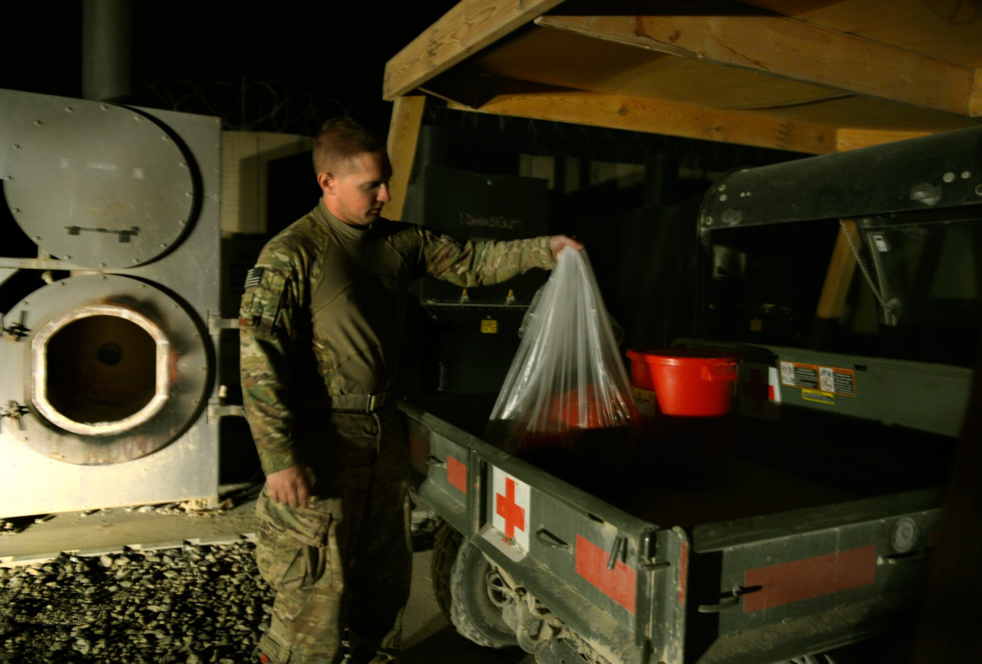 Staff Sgt. Chad Whitehead, carries bio waste from his vehicle to put in an incinerator on the edge of Forward Operating Base Ghazni August 25, 2013. Whitehead is a Forward Surgical Team emergency room technician and NCO in charge of Mortuary affairs here.  He is deployed from Keesler Air Force Base, Miss., and a native of Texarkana, Texas. (U.S. Air Force photo/ Staff Sgt. Stephenie Wade)