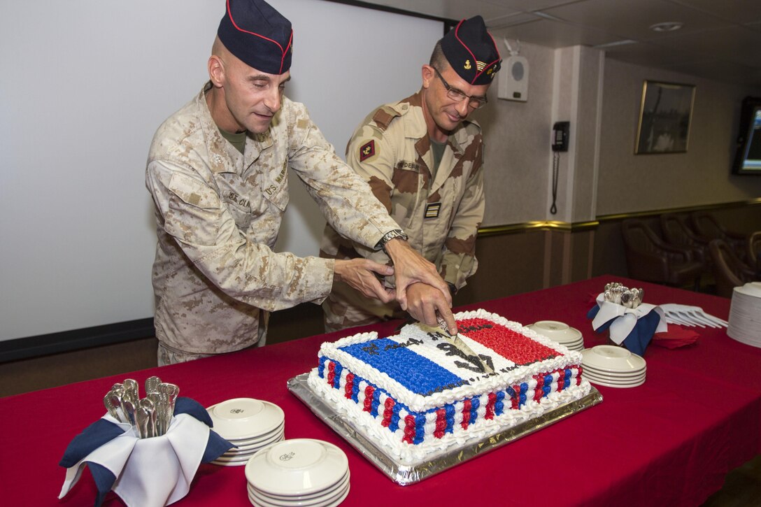 U.S. Marine Corps Col. Matthew G. St. Clair, 26th Marine Expeditionary Unit (MEU) commanding officer, assists French Marine Lt. Col. Rene Debuire with the first cut of a cake during a commemoration ceremony for the Battle of Bazeilles, a widely honored battle in France’s history, in the ward room of the USS Kearsarge (LHD 3), at sea, Aug.31, 2013. The 26th MEU is a Marine Air-Ground Task Force currently assigned to the U.S. 5th Fleet area of responsibility aboard the Kearsarge Amphibious Ready Group serving as a sea-based, expeditionary crisis
response force capable of conducting amphibious operations across the full range of military operations. (U.S. Marine Corps photo by Cpl. Kyle N. Runnels/Released)
