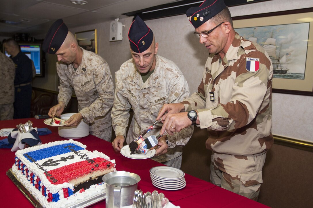 U.S. Marine Corps Col. Matthew G. St. Clair, center, commanding officer of the 26th Marine Expeditionary Unit (MEU), cuts a cake with French Marine Lt. Col. Rene Debuire during a commemoration ceremony for the Battle of Bazeilles, a widely honored battle in France’s history, in the ward room of the USS Kearsarge (LHD 3), at sea, Aug. 31, 2013. The 26th MEU is a Marine Air-Ground Task Force currently assigned to the U.S. 5th Fleet area of responsibility aboard the Kearsarge Amphibious Ready Group serving as a sea-based, expeditionary crisis response force capable of conducting amphibious operations across the full range of military operations. (U.S. Marine Corps photo by Cpl. Kyle N.
Runnels/Released)
