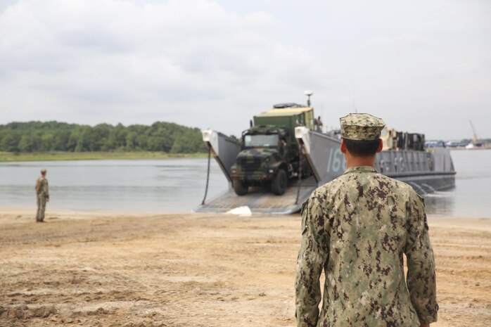 A sailor with the Navy’s Beach Departure Team 5 watches over a Marine with Combat Logistics Battalion 24, 2nd Marine Logistics Group as he loads a Medium Tactical Vehicle Replacement onto a Landing Craft Utility aboard Naval Amphibious Base Little Creek, Va., during a Defense Support of Civil Authorities, or DSCA, training exercise, Aug. 21, 2013. The battalion performed loading and offloading exercises in preparation for possible DSCA missions during natural disaster disasters.