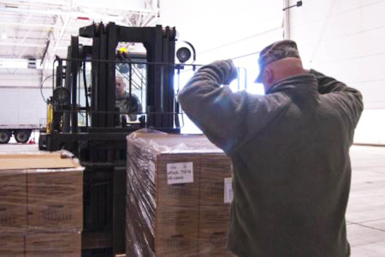 Staff Sgt. Joshua Wishmyer signals to his brother Staff Sgt. John Wishmyer as he moves a pallet of boxed meals at the West Virginia Air National Guard's 167th Airlift Wing based in Martinsburg W.Va., Nov. 1, 2012.