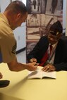 Original Montford Point Marine Turner G. Blount signs a book when he visited Marine Corps Base Camp Johnson for Montford Point Day, Aug. 22. During Montford Point Day, the original Montford Point Marines shared their experiences and signed books. 