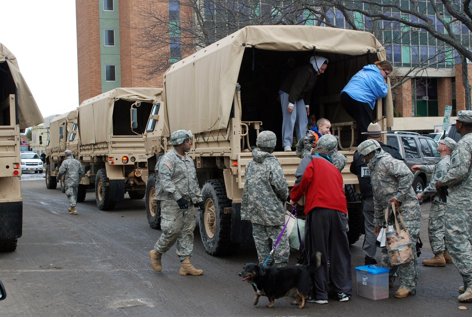 New York Army National Guard soldiers assist residents arriving by military vehicle to Long Beach City Hall for evacuation to shelters. Guard members are assisting throughout the flood-ravaged region.
