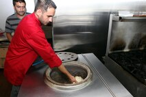 Chef Mohamed Ajmal puts naan read into a traditional oven at Naan and Kabob, Aug. 14. Naan bread is first flattend, then stuck to the side the oven to cook. 