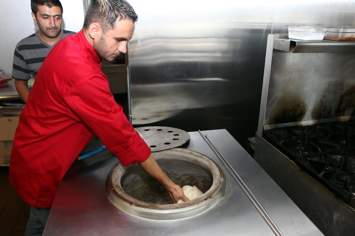 Chef Mohamed Ajmal puts naan read into a traditional oven at Naan and Kabob, Aug. 14. Naan bread is first flattend, then stuck to the side the oven to cook. 