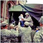 Spc. Jesse de la Cruz, center on truck, assists in evacuating a toddler at a rescue mission at Hoboken, N.J., Oct. 31. New Jersey National Guard soldiers from Foxtrot Company, 250th Brigade Support Battalion, were the first company from the NJNG to arrive in Hoboken. They successfully completed more than 25 missions, which included rescues and delivering food and water to local shelters. In addition, de la Cruz rescued a pregnant woman going into labor, who was held up in her home for two days without food, water, and electricity. The unit immediately transported her to the shelter hospital for medical treatment.